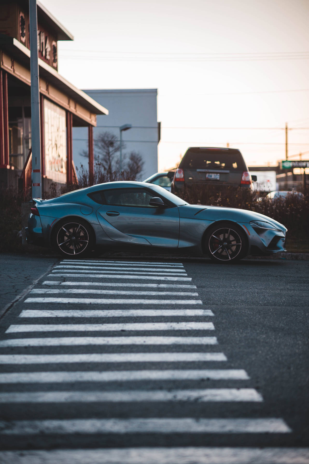 銀色跑車在日落時分停泊在街上，有行人穿越道。 — Toyota Supra 壁紙