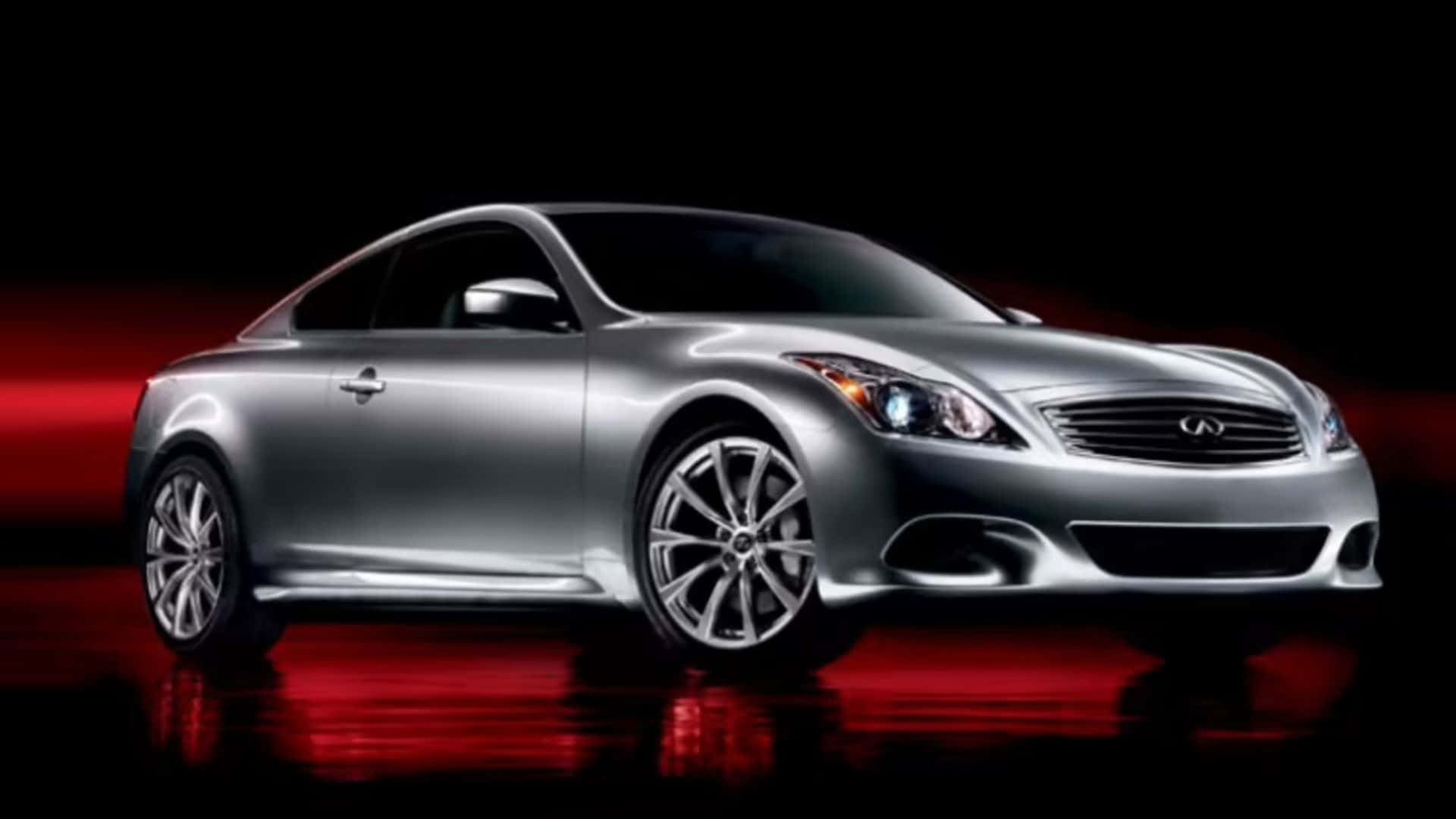 Infiniti G37 桌布 壁紙 — 一輛時尚的銀色運動轎跑車在戲劇性的紅色燈光下，在帶有反射地板的黑色背景上閃閃發光。