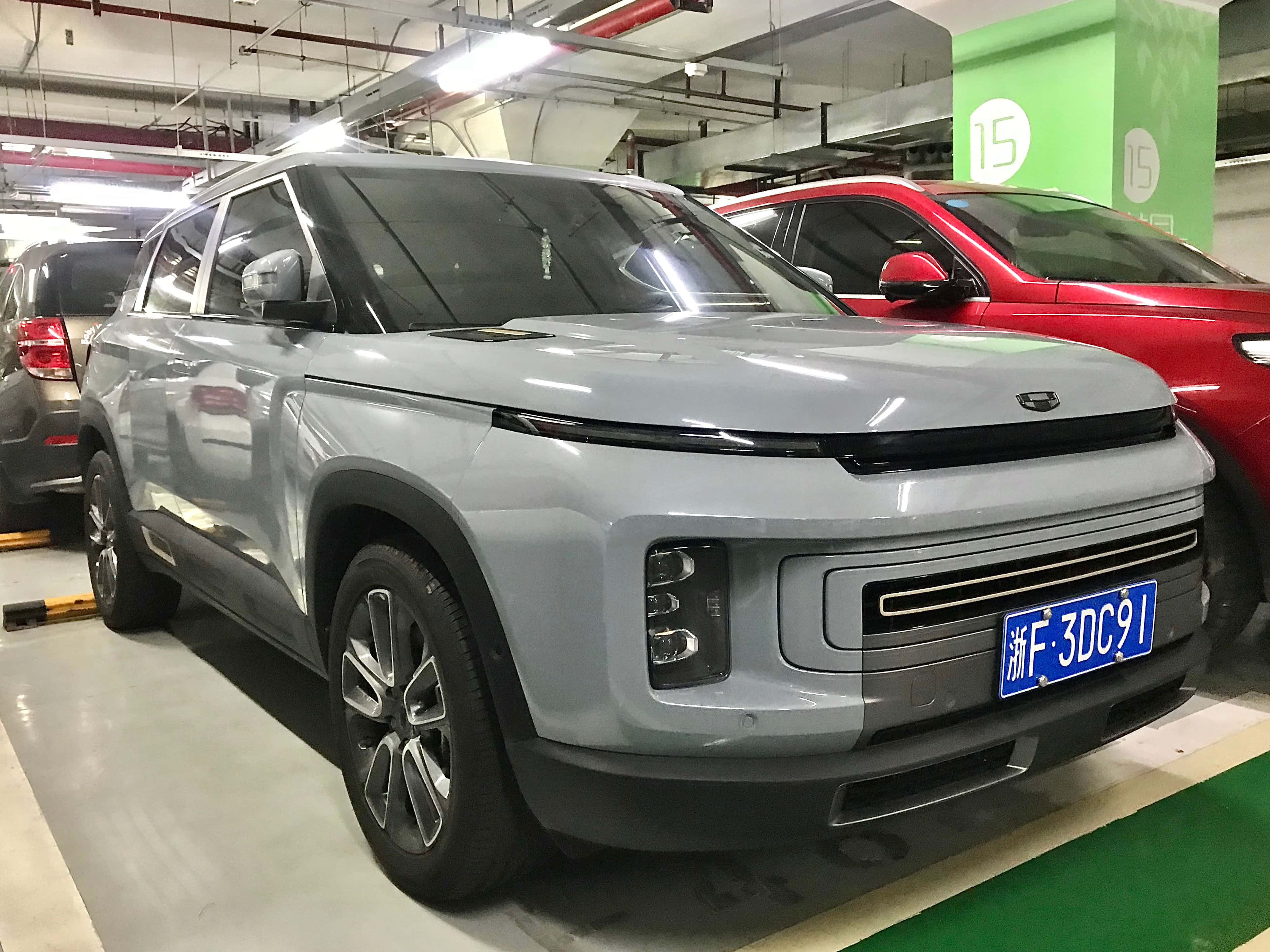 Geely Icon 桌布 壁紙 — 一輛時尚的銀色SUV停放在光線充足的地下停車場，旁邊有一輛紅色汽車。