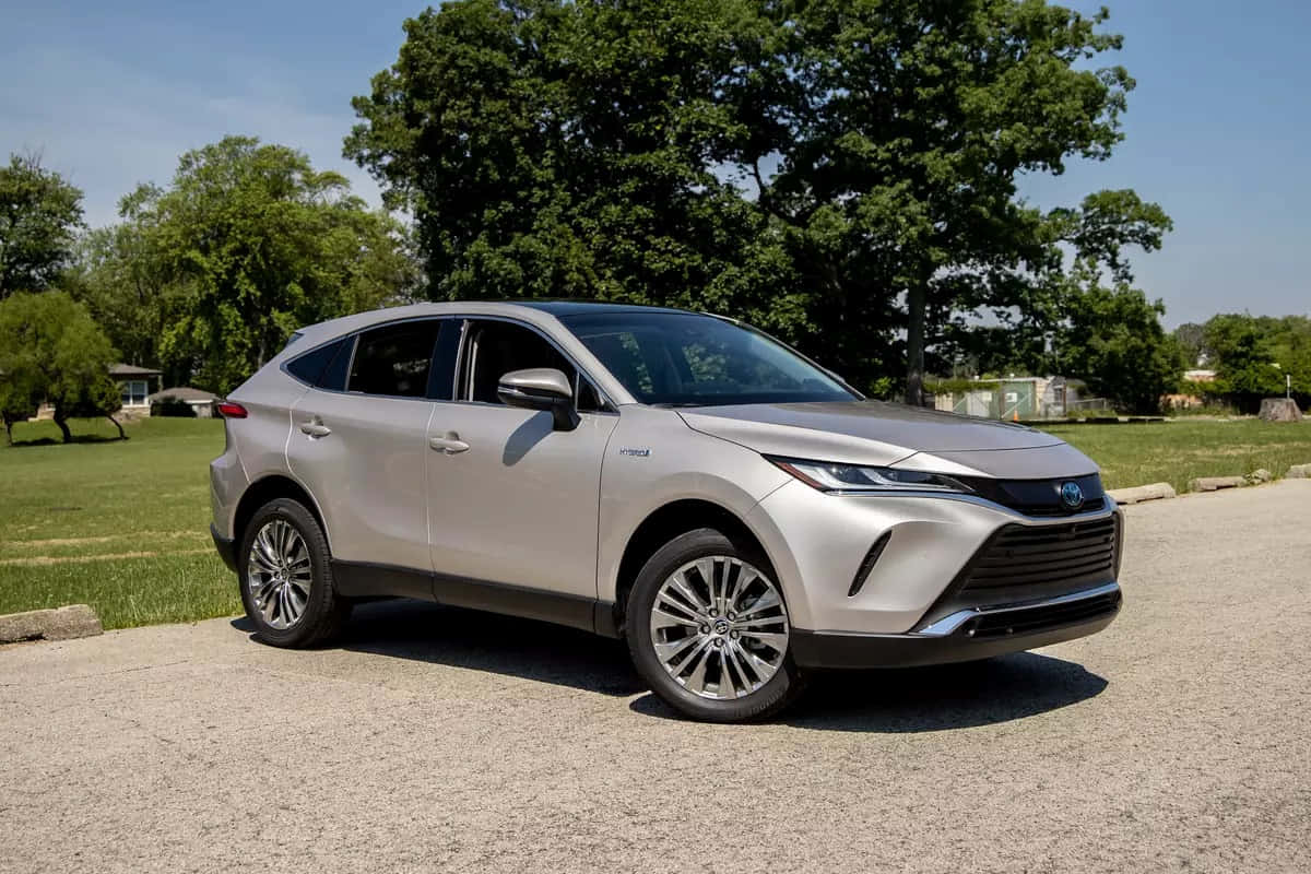 銀色豐田RAV4混合動力SUV停放在碎石上，有綠樹和藍天。 — Toyota Supra Mk4 壁紙