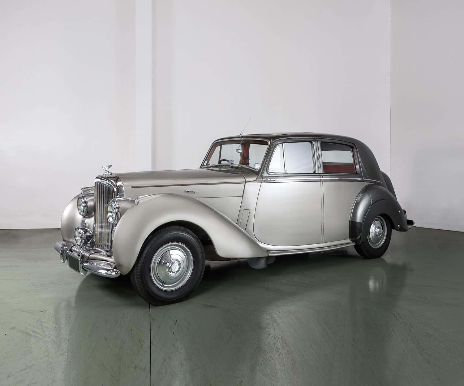 Bentley Mark Vi 桌布 壁紙 — 一輛時尚的銀色復古賓利轎車，帶有鍍鉻飾邊和黑色飾條，矗立在簡約的攝影棚空間中。