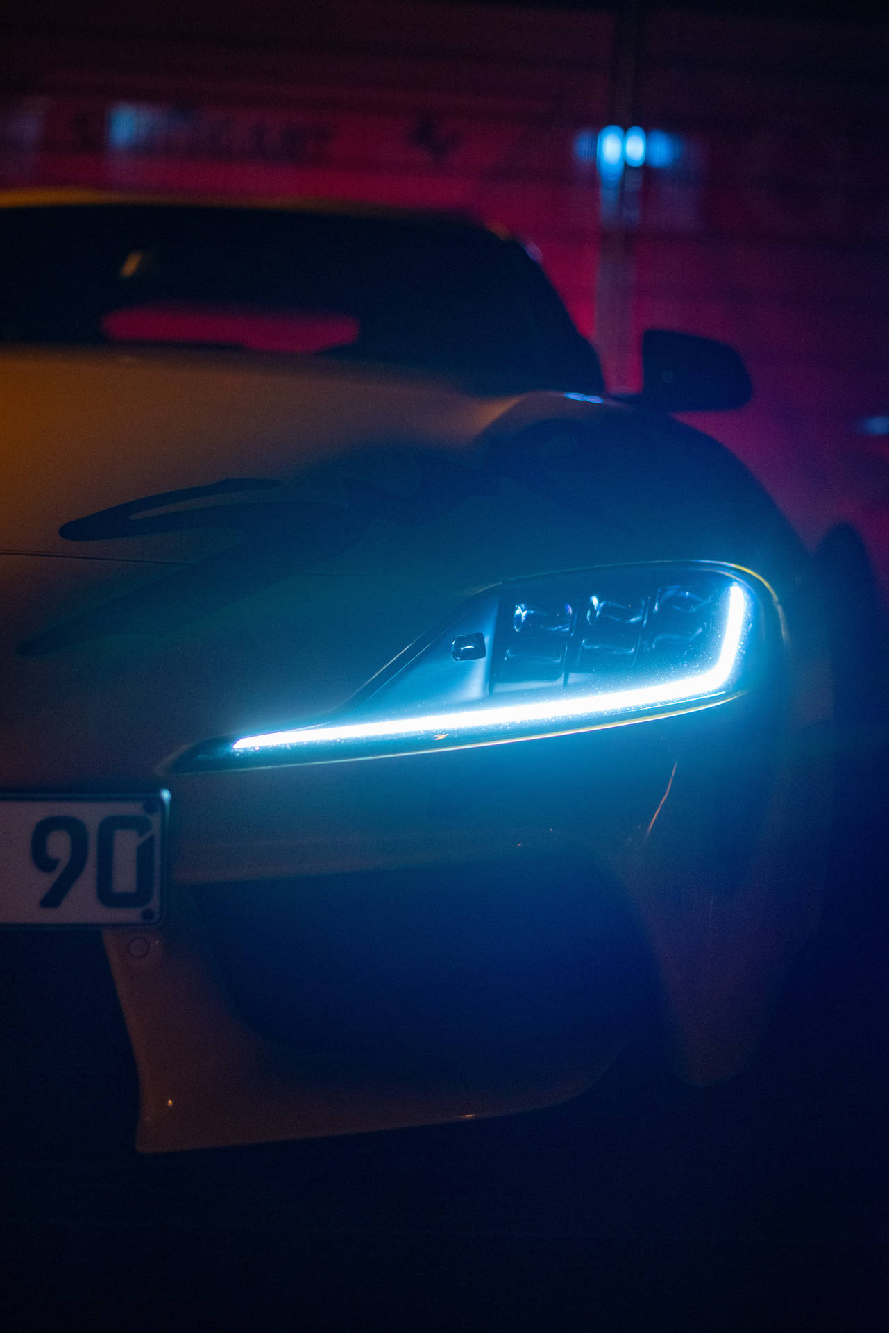 時尚跑車在黑暗的霓虹車庫中發出藍色車頭燈。 — Toyota Supra 壁紙
