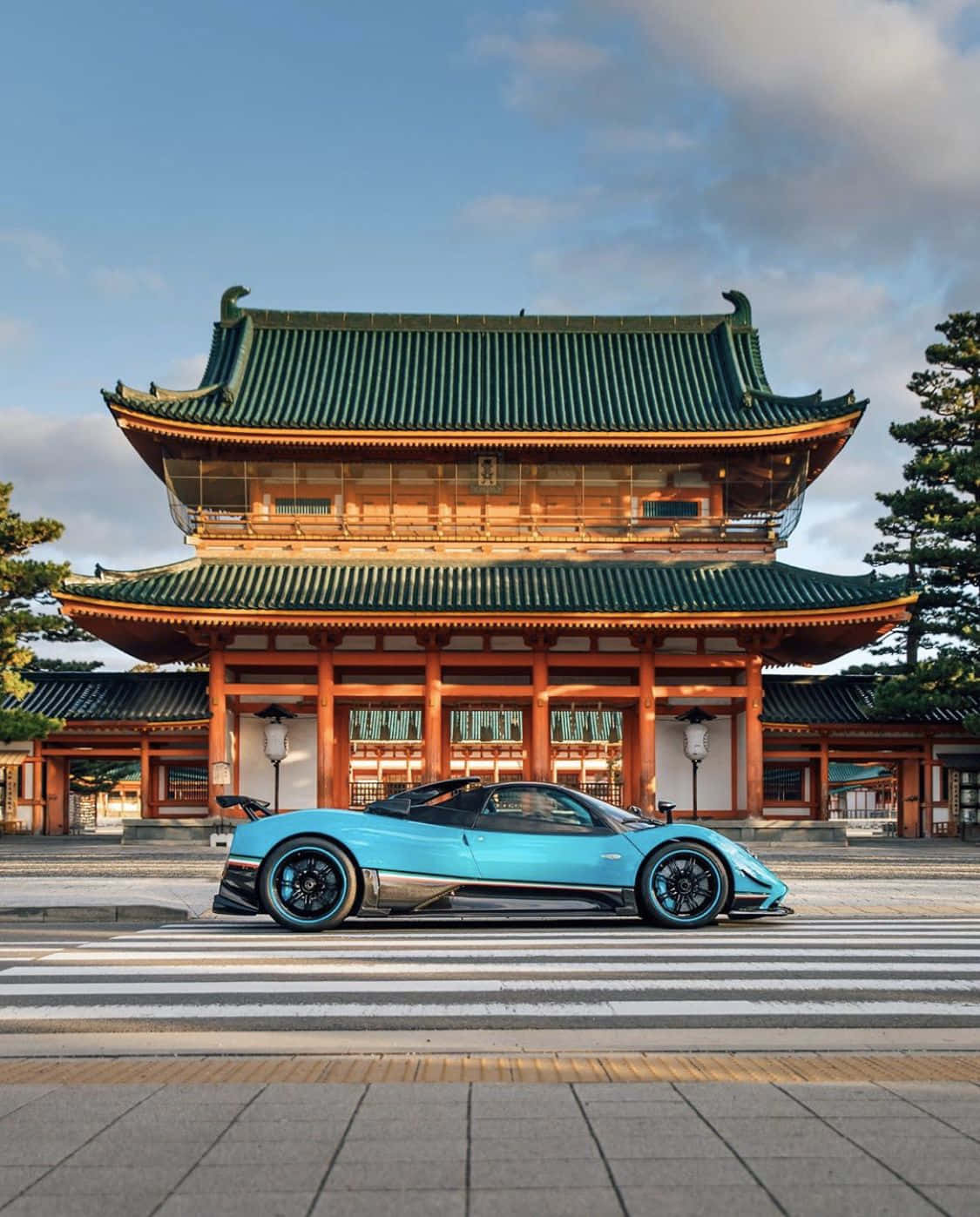 Pagani Zonda Tricolore 桌布 壁紙 — 一架流線型青綠色超跑停放在傳統日本寺廟前，寺廟有綠色瓦頂，天空清澈湛藍。