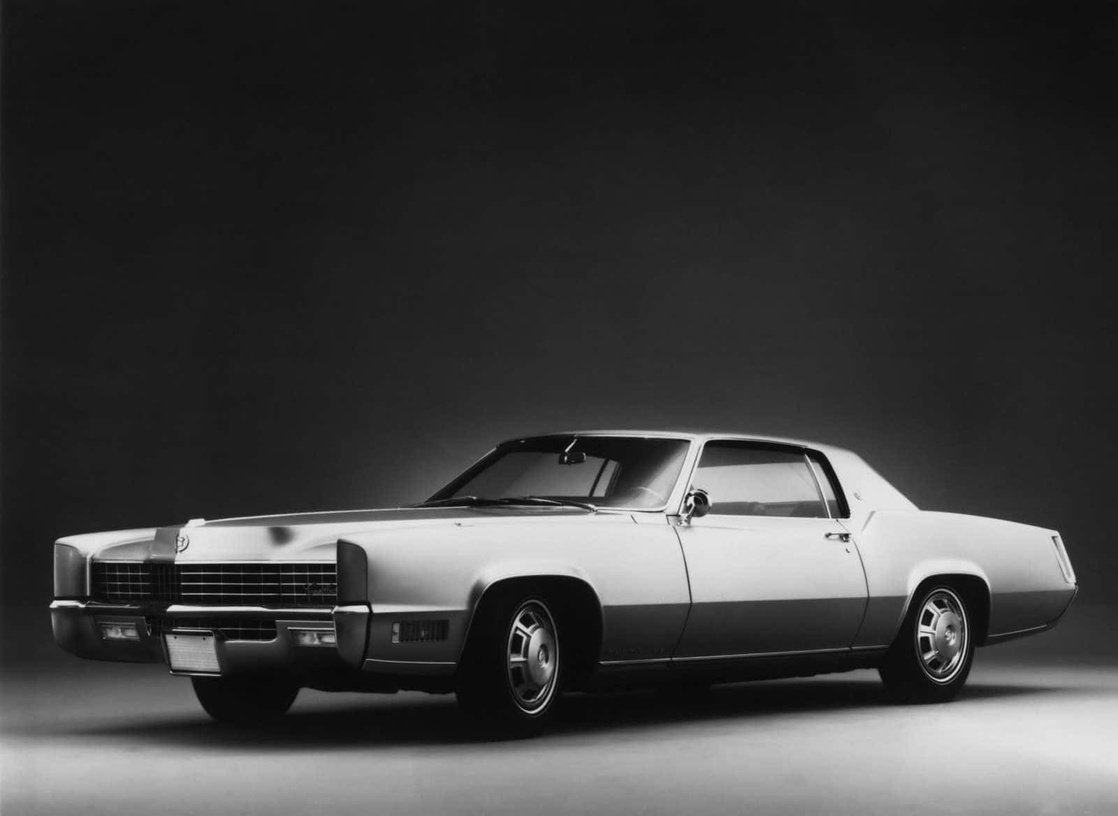 Cadillac Eldorado 桌布 壁紙 — 時尚復古車在單色工作室燈光下，於深色漸變背景中閃耀。