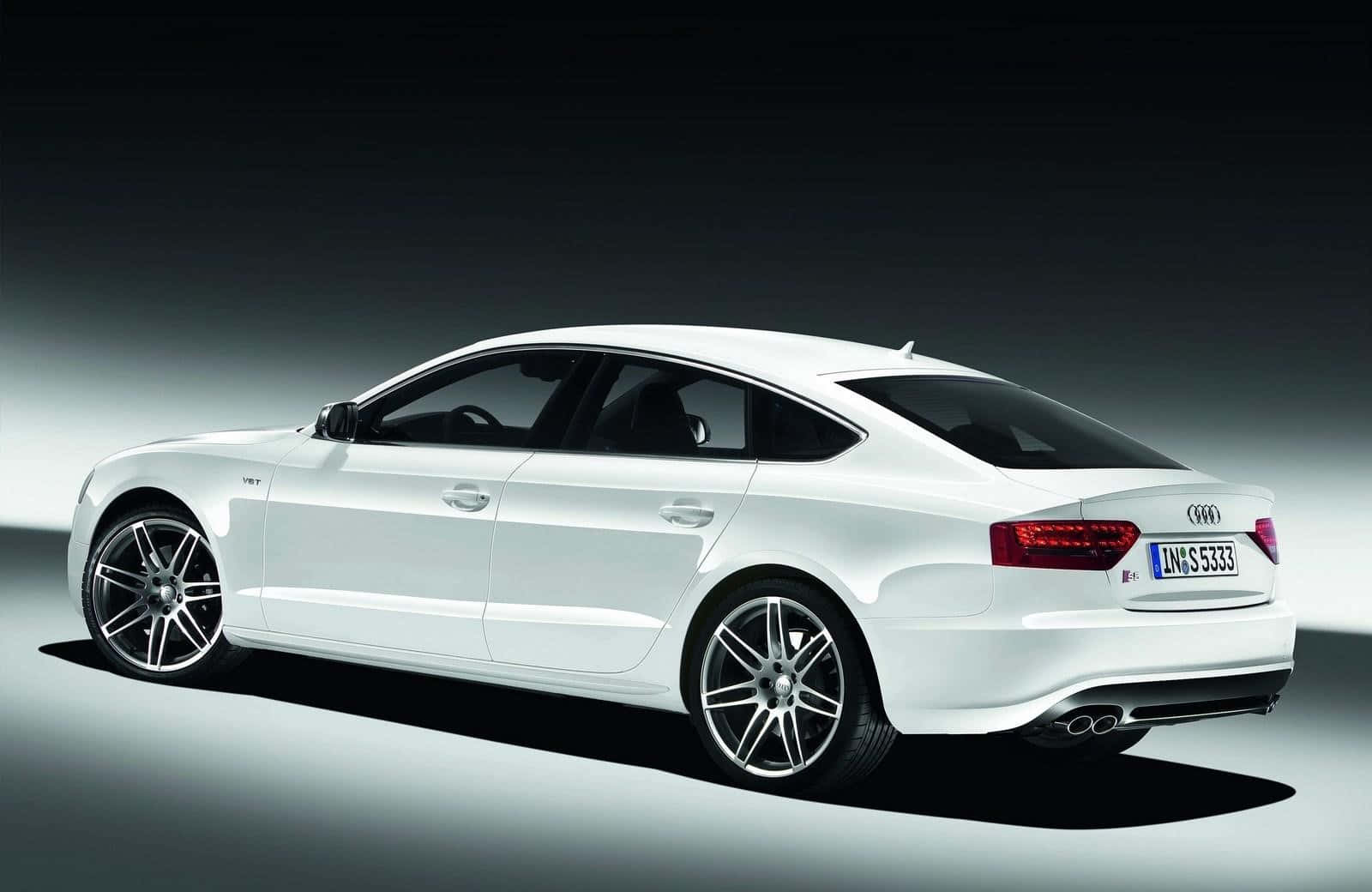 Audi A5 桌布 壁紙 — 一輛時尚的白色奧迪轎車在極簡主義的工作室中滑行，配有戲劇性的聚光燈和深色漸變背景。