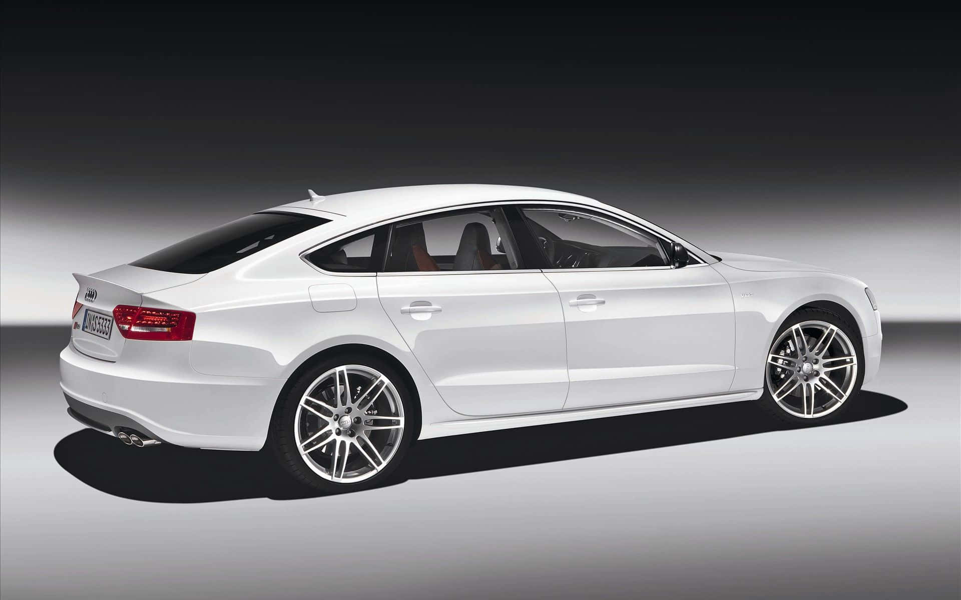 Audi A5 桌布 壁紙 — 一輛時尚的白色奧迪轎車以側面輪廓展示，背景為漸變工作室背景，帶有戲劇性燈光。
