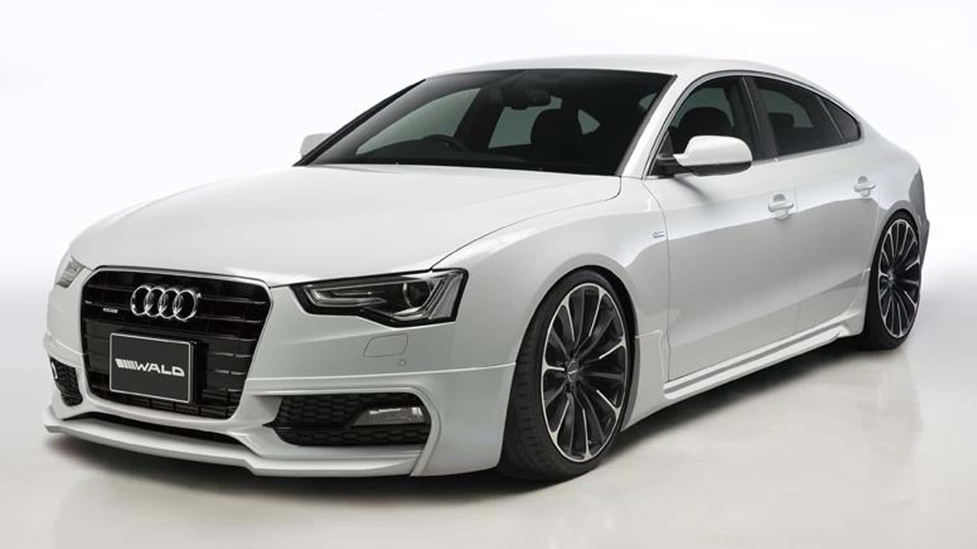 Audi A5 桌布 壁紙 — 一輛時尚的白色奧迪轎車，配備黑色輪圈和Wald改裝零件，在潔淨的白色工作室背景前擺拍。