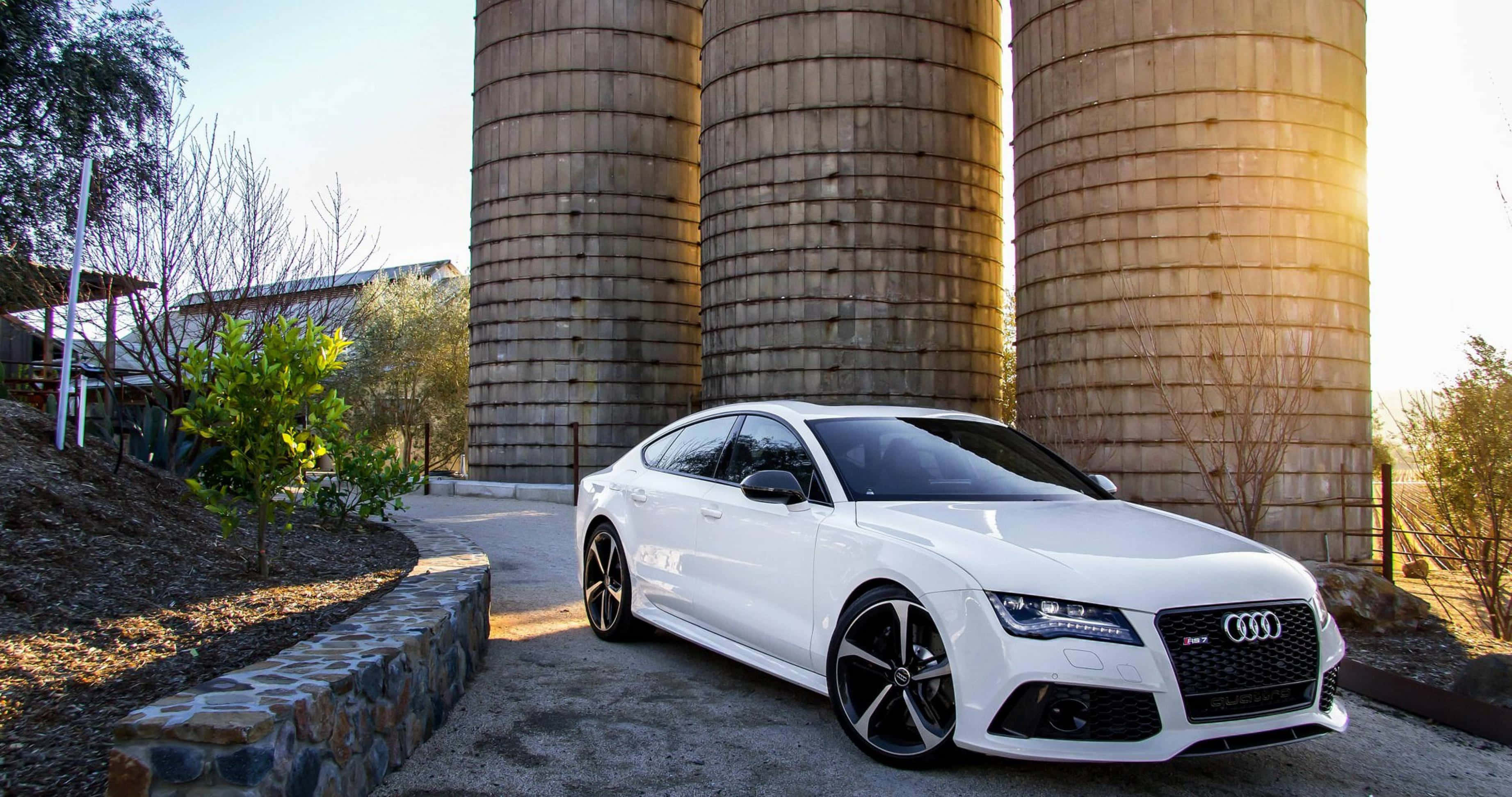 Audi A4 桌布 壁紙 — 一輛時尚的白色奧迪跑車停放在沐浴在金色日落光線中的高聳木製穀倉前。