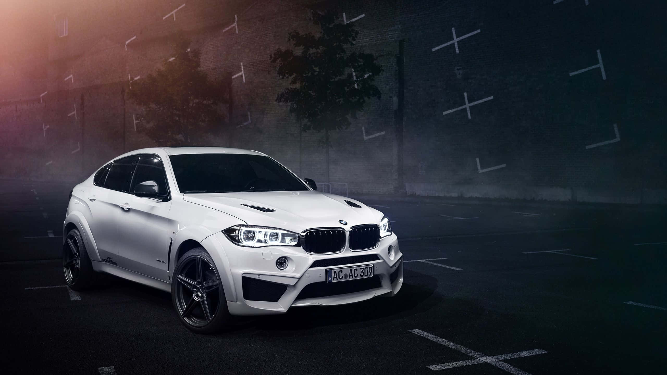 Bmw X6 桌布 壁紙 — 一輛時尚的白色BMW X6M跑車在戲劇性的夜間燈光下，於空蕩的城市停車場中閃閃發光。