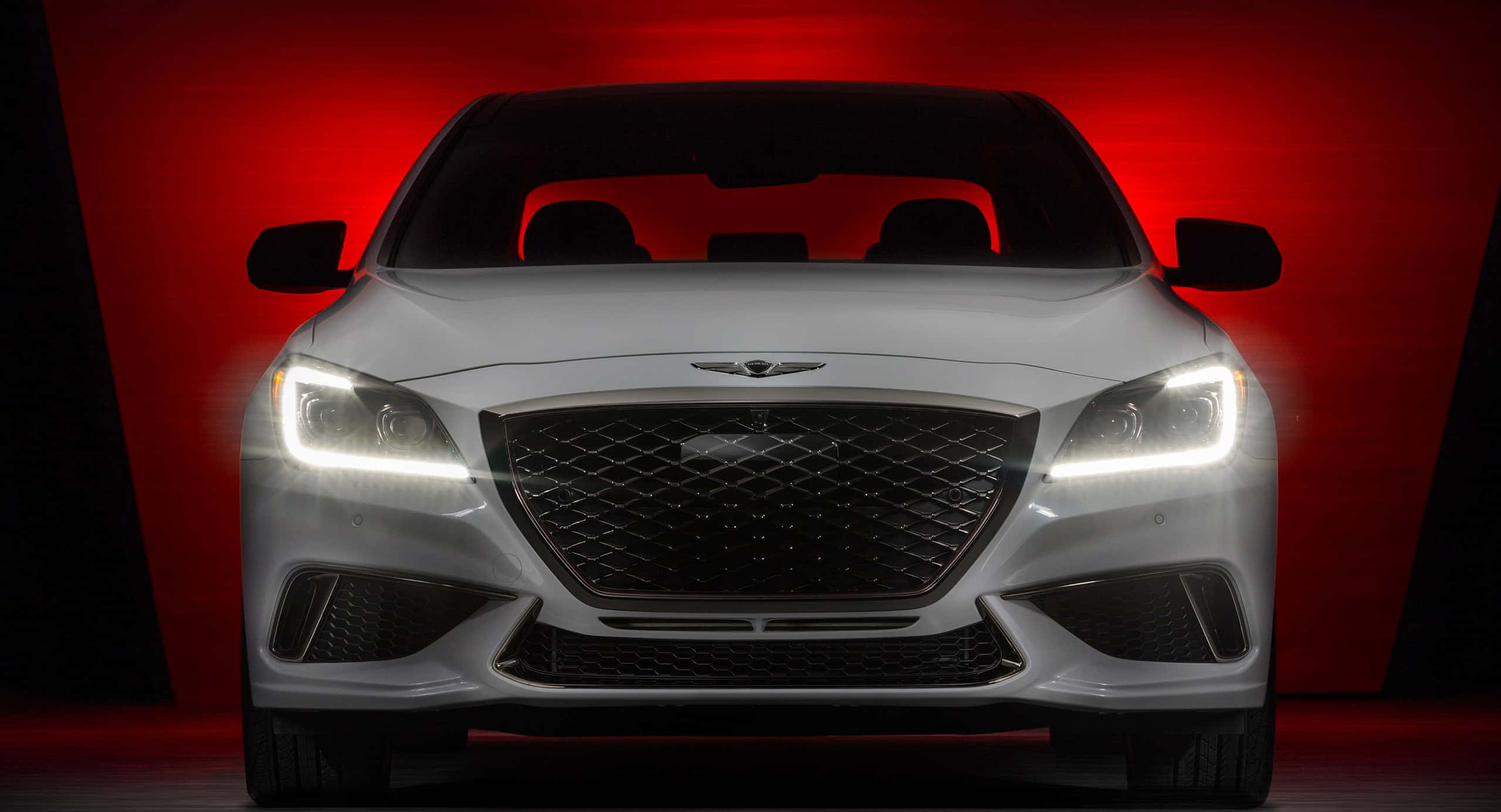 Genesis G80 桌布 壁紙 — 一輛時尚的白色Genesis汽車正面朝前，配備發光的車頭燈，背景是戲劇性的紅色照明工作室。
