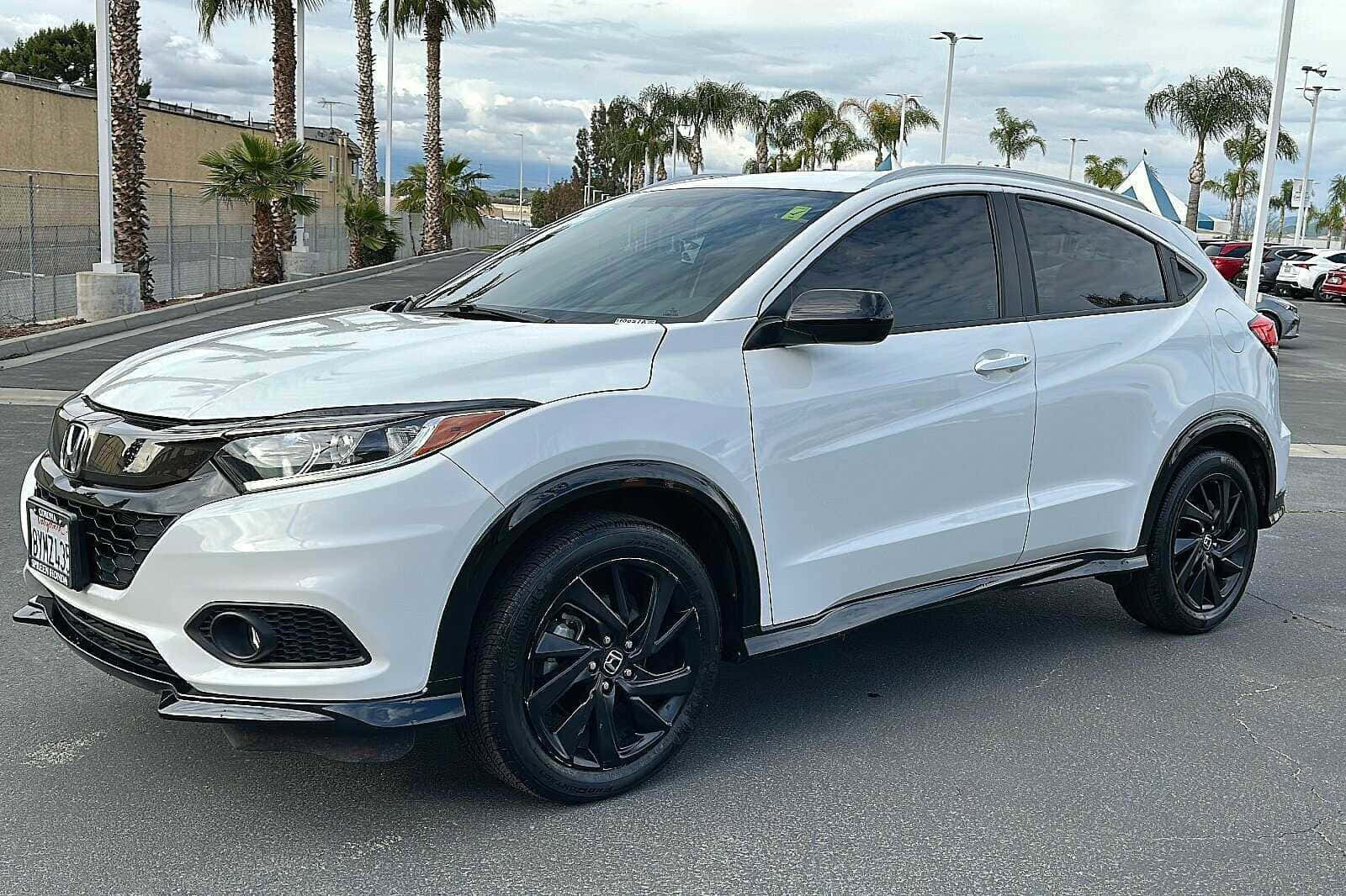 Honda Hr-v 桌布 壁紙 — 一輛時尚的白色本田 HR-V 帶有黑色飾件，停泊在停車場，背景是陰天和棕櫚樹。