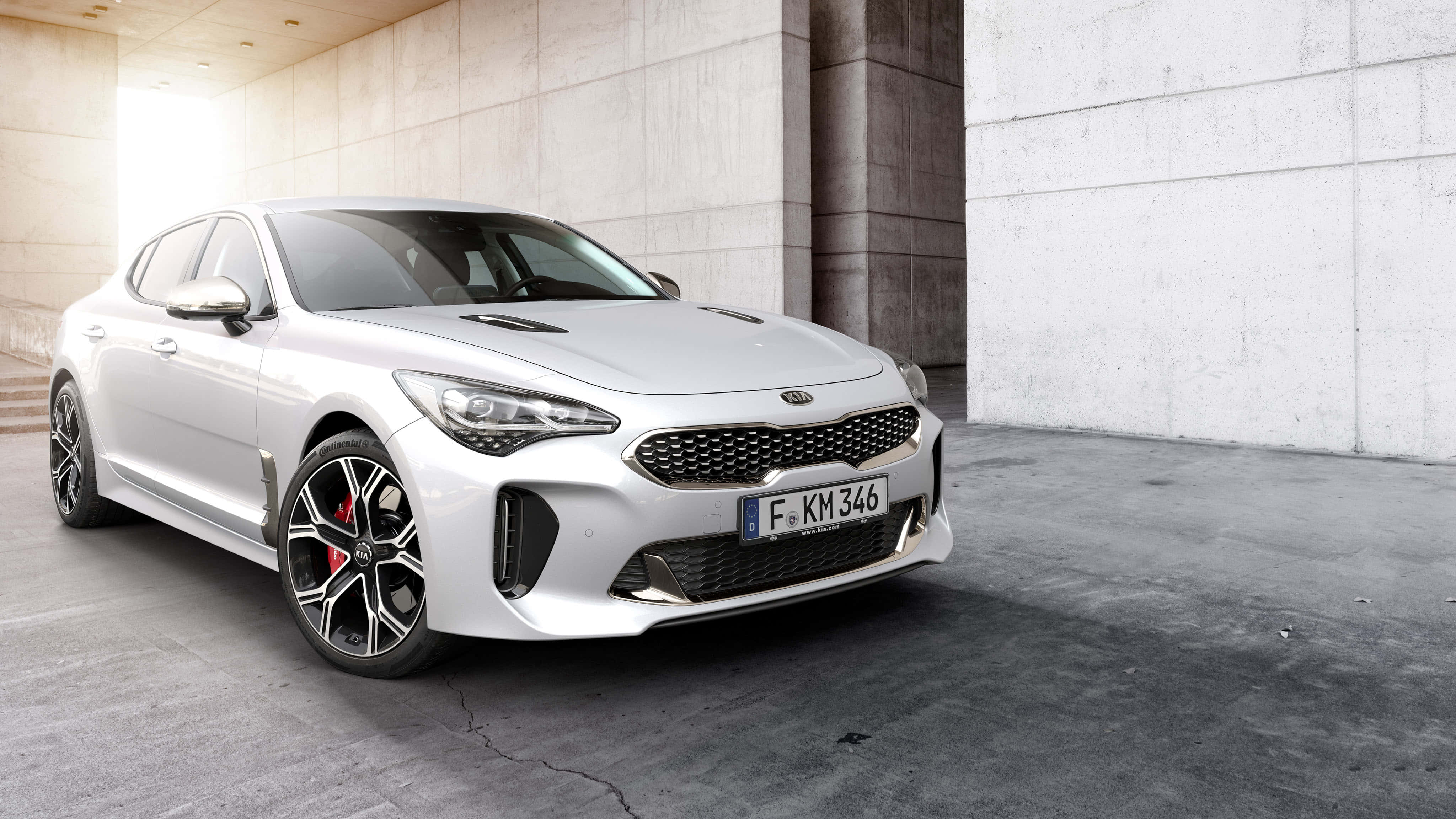 Kia Stinger 桌布 壁紙 — 一輛時尚的白色Kia Stinger跑車停放在現代混凝土車庫中，陽光照射進來。