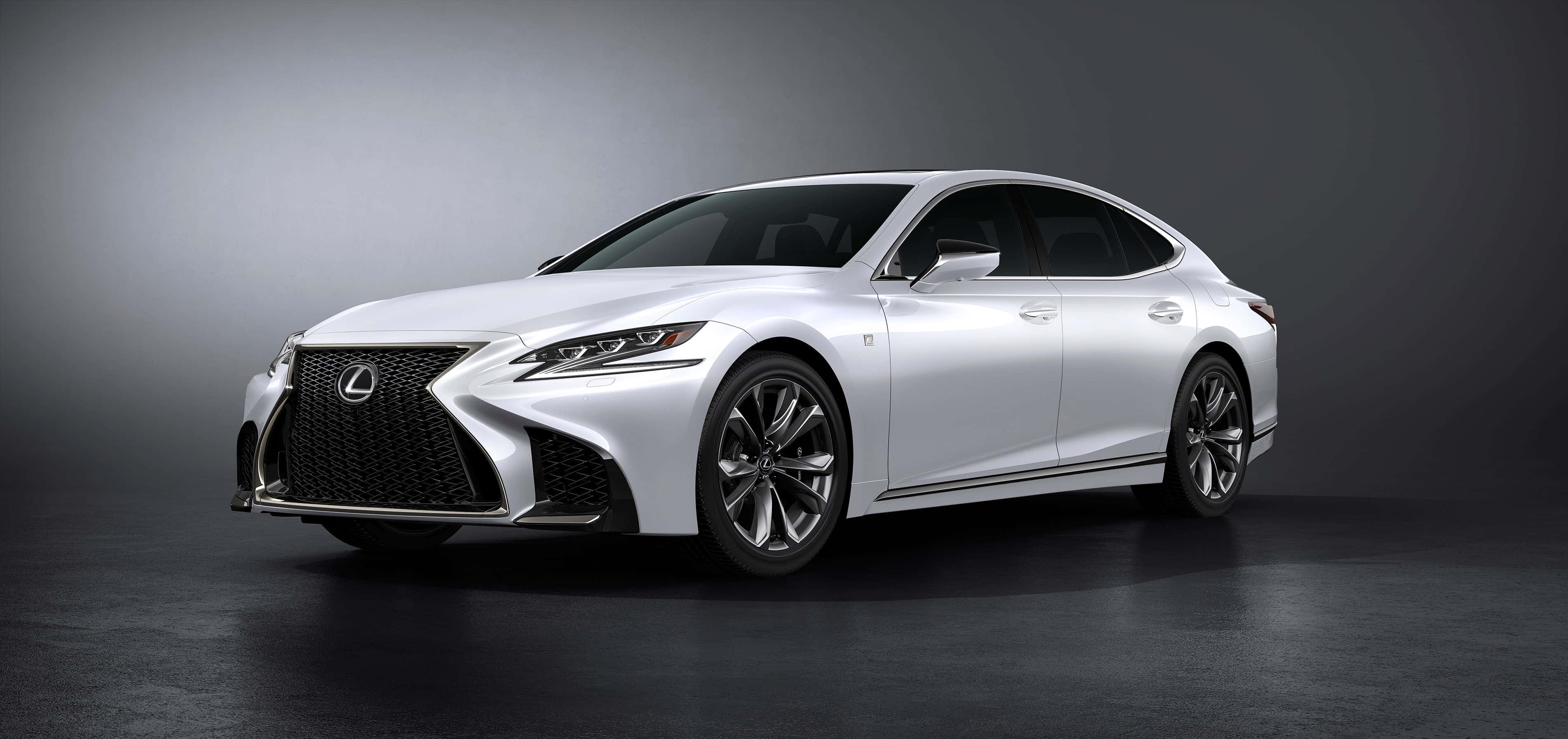 Lexus Ls 500 桌布 壁紙 — 一輛時尚的白色Lexus轎車在攝影棚燈光下，於深灰色漸變背景前閃閃發光。