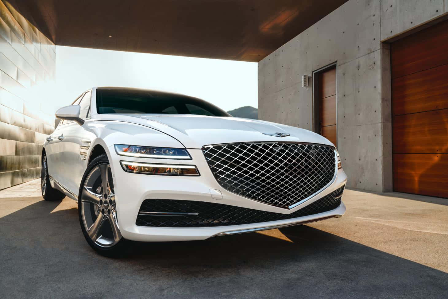 Genesis G80 桌布 壁紙 — 一架時尚的白色豪華轎車停放在現代混凝土車棚下，溫暖的陽光在其拋光表面上投下陰影。
