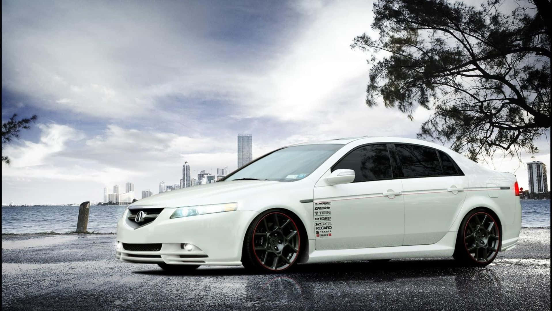 Acura Tl 桌布 壁紙 — 一輛時尚的白色改裝轎車配黑色輪圈，停泊在潮濕的海岸道路上，天空多雲，背景是城市天際線。