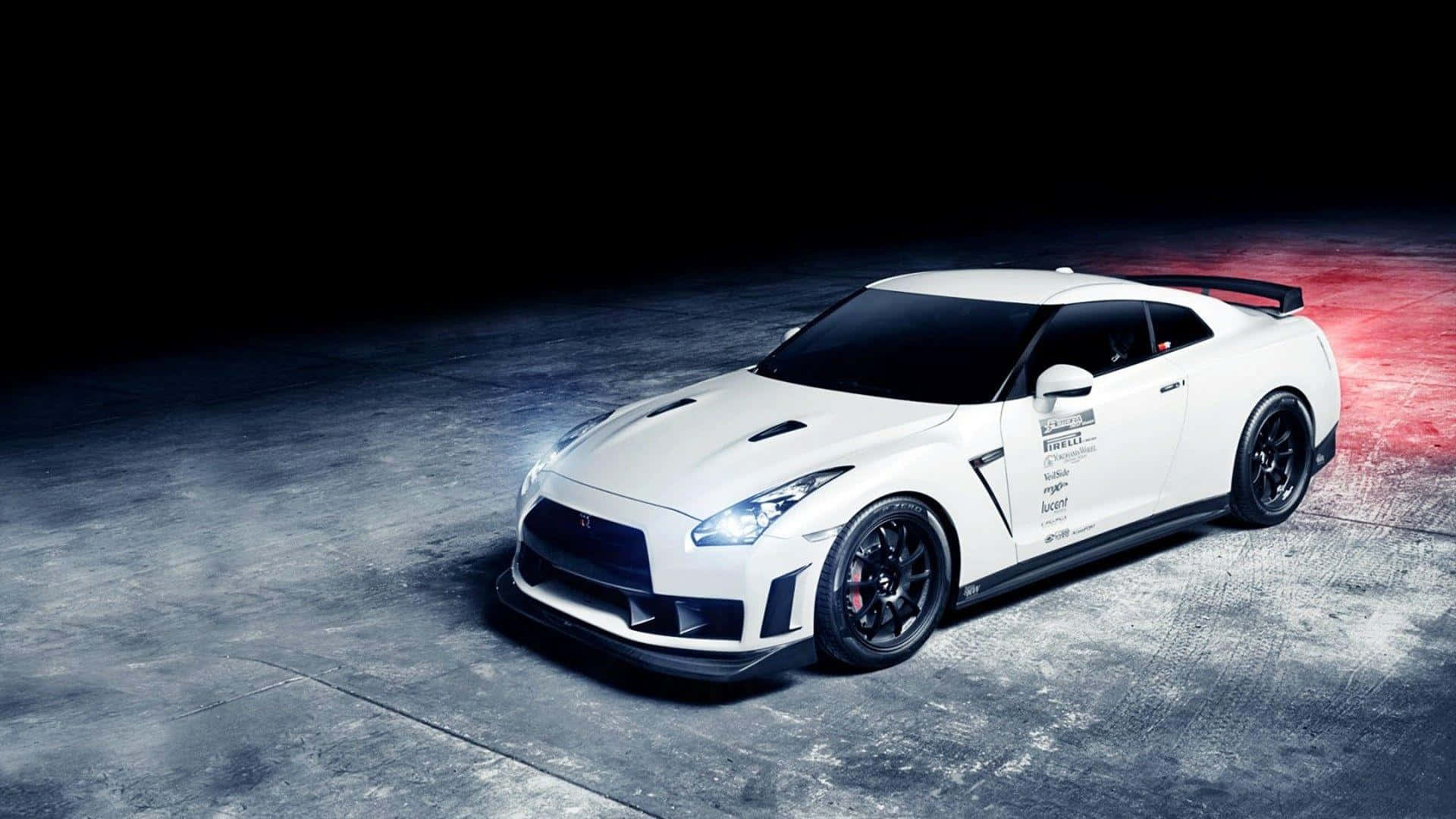 白色日產GT-R賽車，帶有黑色車輪和紅色制動卡鉗，在工作室燈光下的深色混凝土上。 — 日產GTR 壁紙