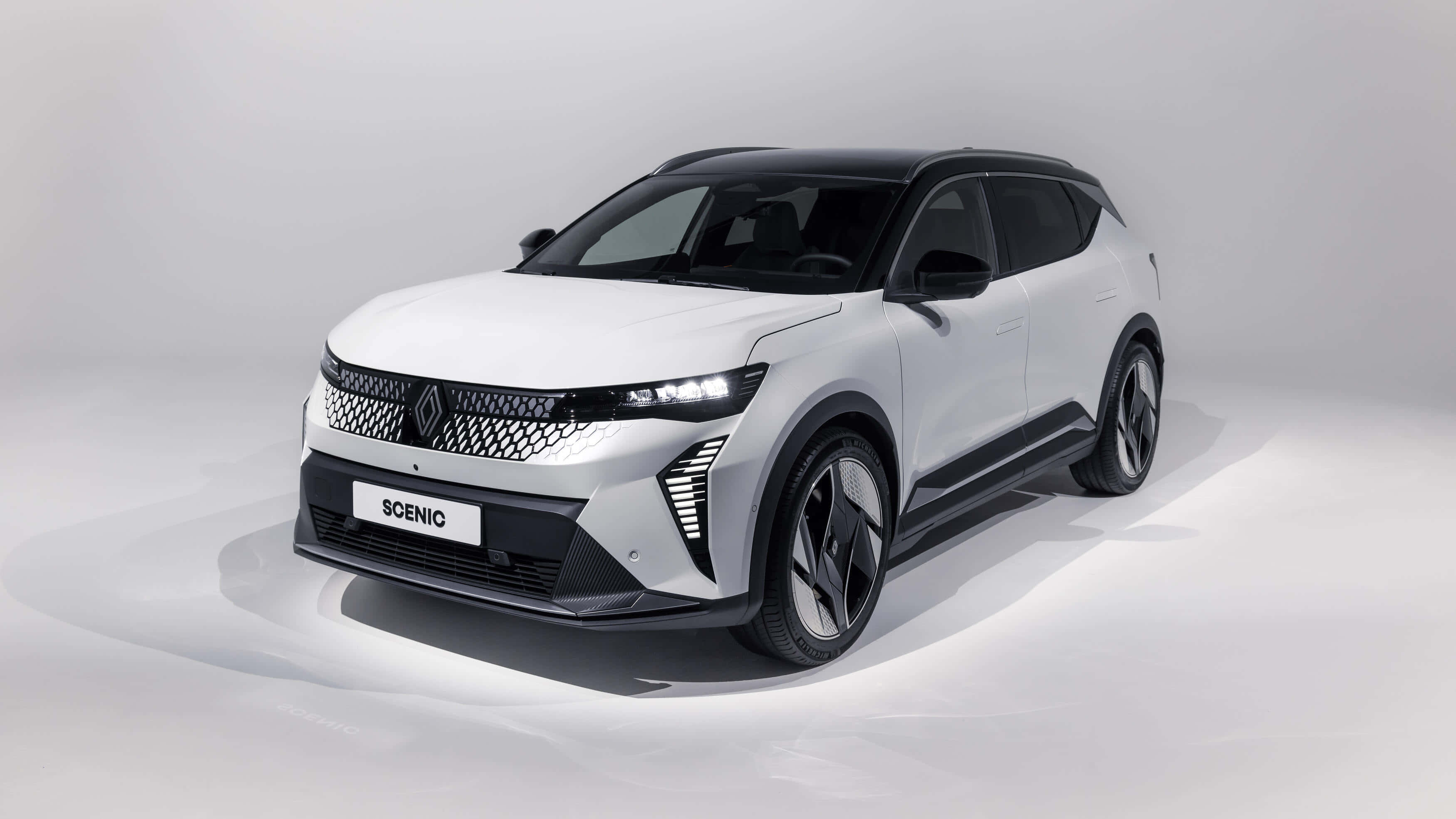 Renault Scenic 桌布 壁紙 — 一部時尚的白色雷諾Scenic SUV，帶有黑色飾邊和現代LED頭燈，在簡約的攝影棚環境中展示。