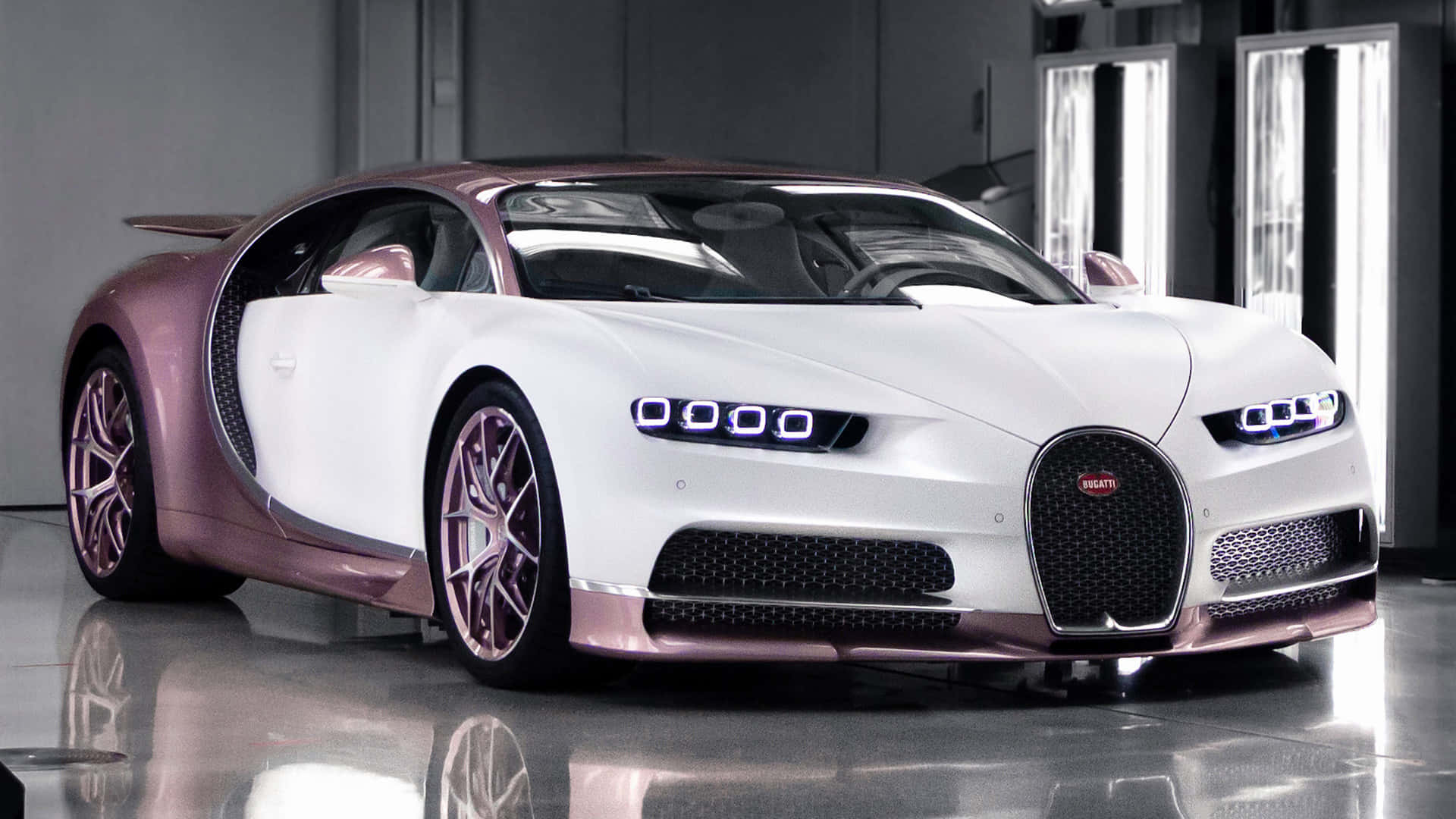 Bugatti Chiron 桌布 壁紙 — 一輛時尚的白色和玫瑰金色布加迪Chiron，帶有發光的藍色車頭燈，停在一個極簡主義的工作室中，地板具有反射效果。