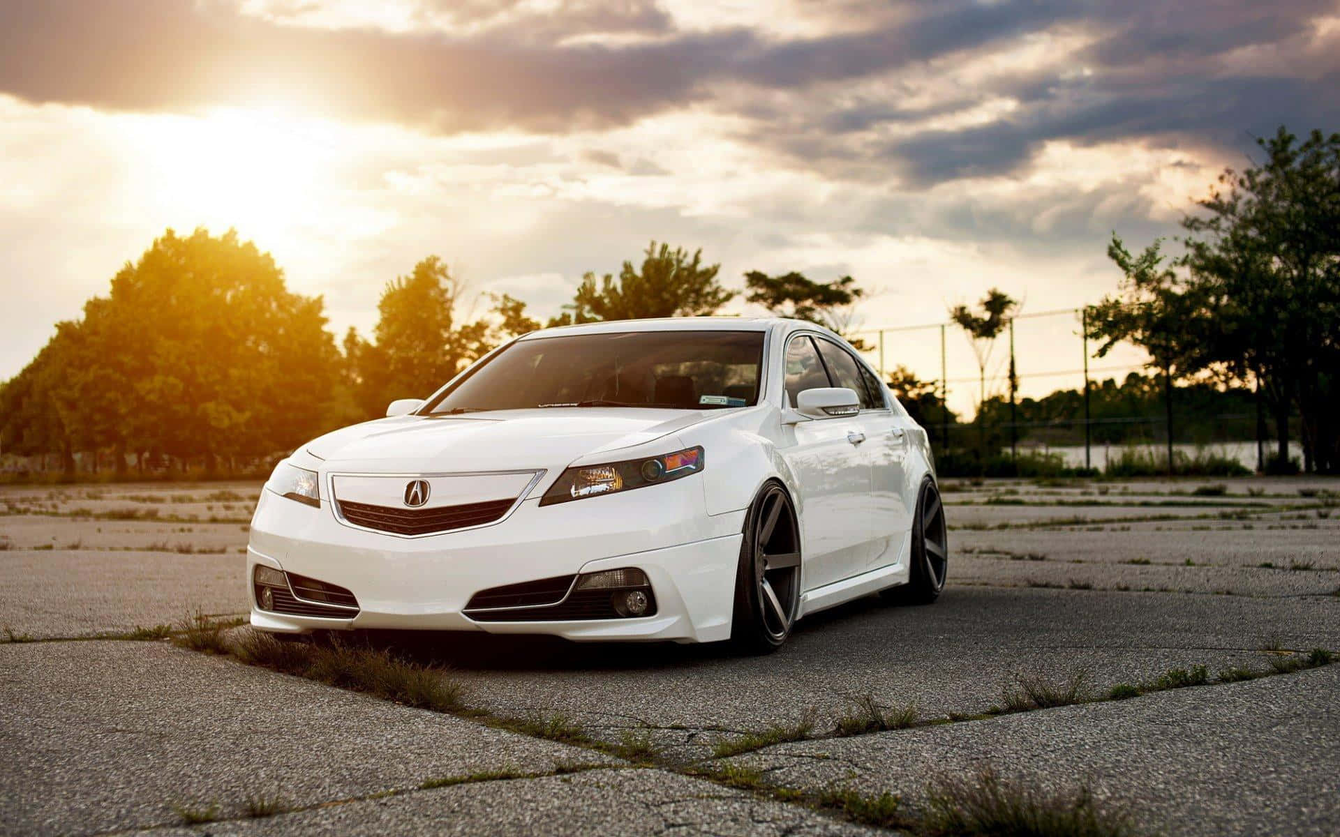 Acura Tsx 桌布 壁紙 — 一輛流線型白色跑車停泊在裂開的路面上，背景是壯麗的日落天空，金光閃耀。