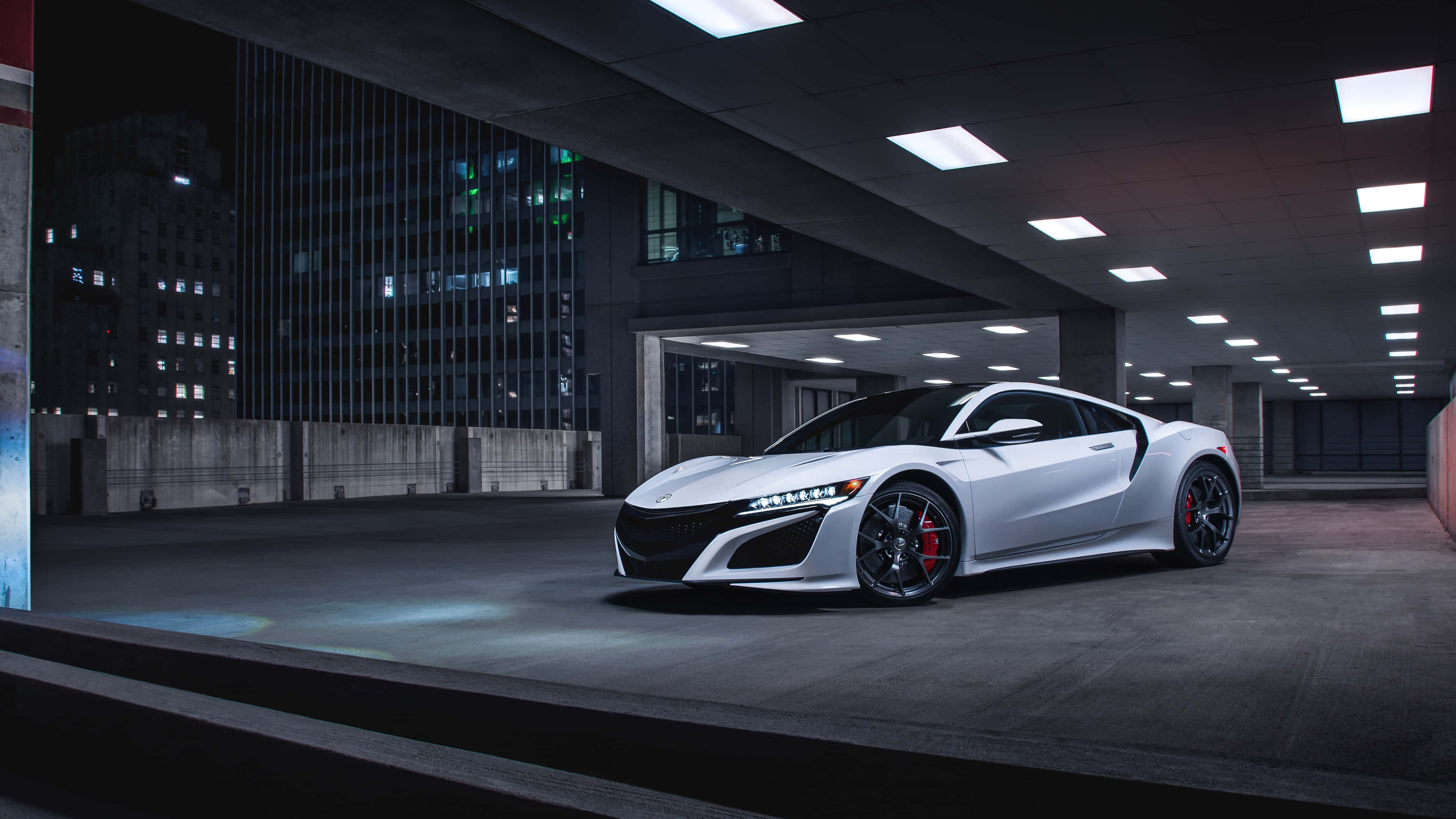 Acura Nsx 桌布 壁紙 — 一輛時尚的白色跑車，帶紅色制動卡鉗，夜間停放在現代城市停車結構下。