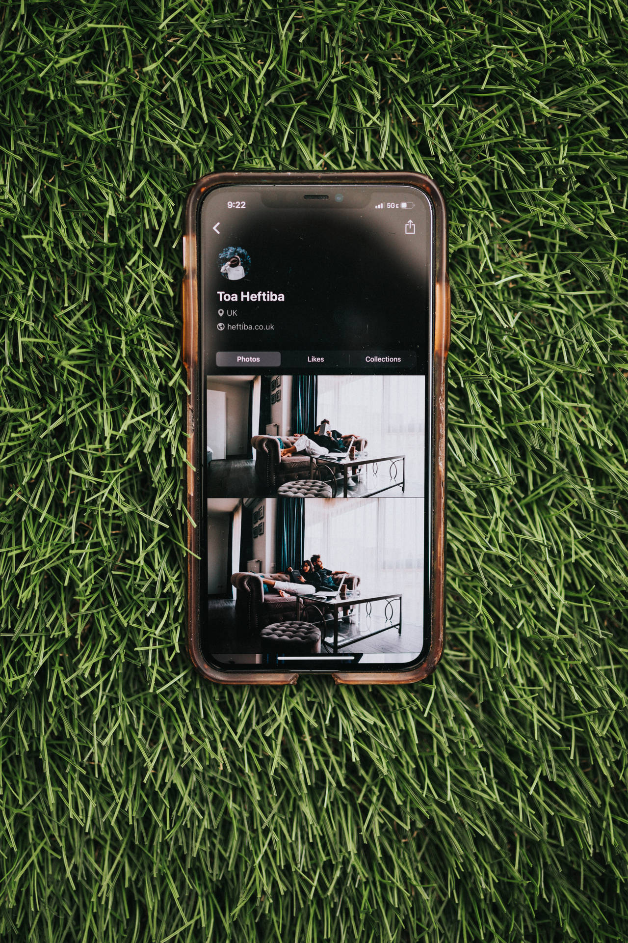 智慧型手機在綠色草地上顯示Instagram個人資料。 — iPhone X 壁紙