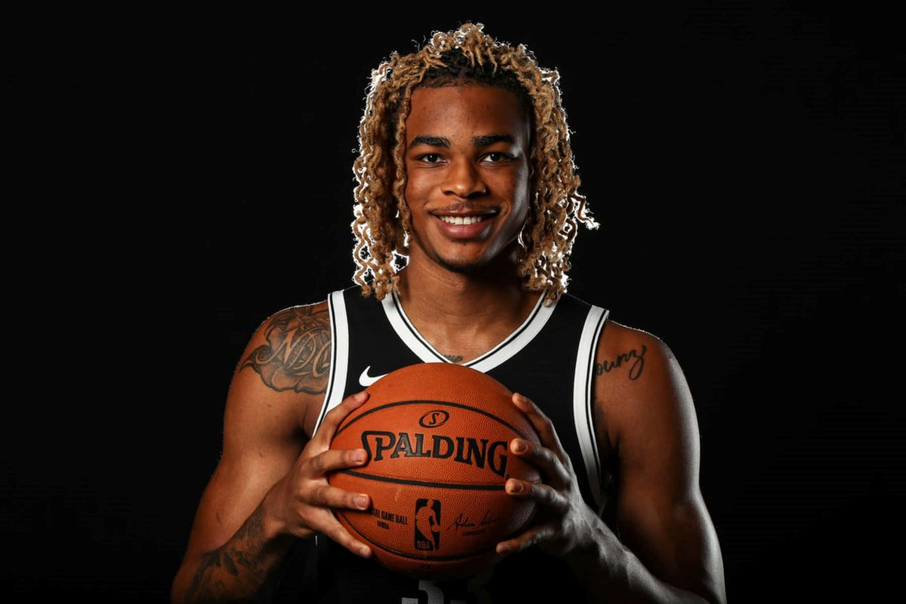 年輕籃球運動員在工作室肖像中拿著 Spalding 籃球。 — NBA 壁紙
