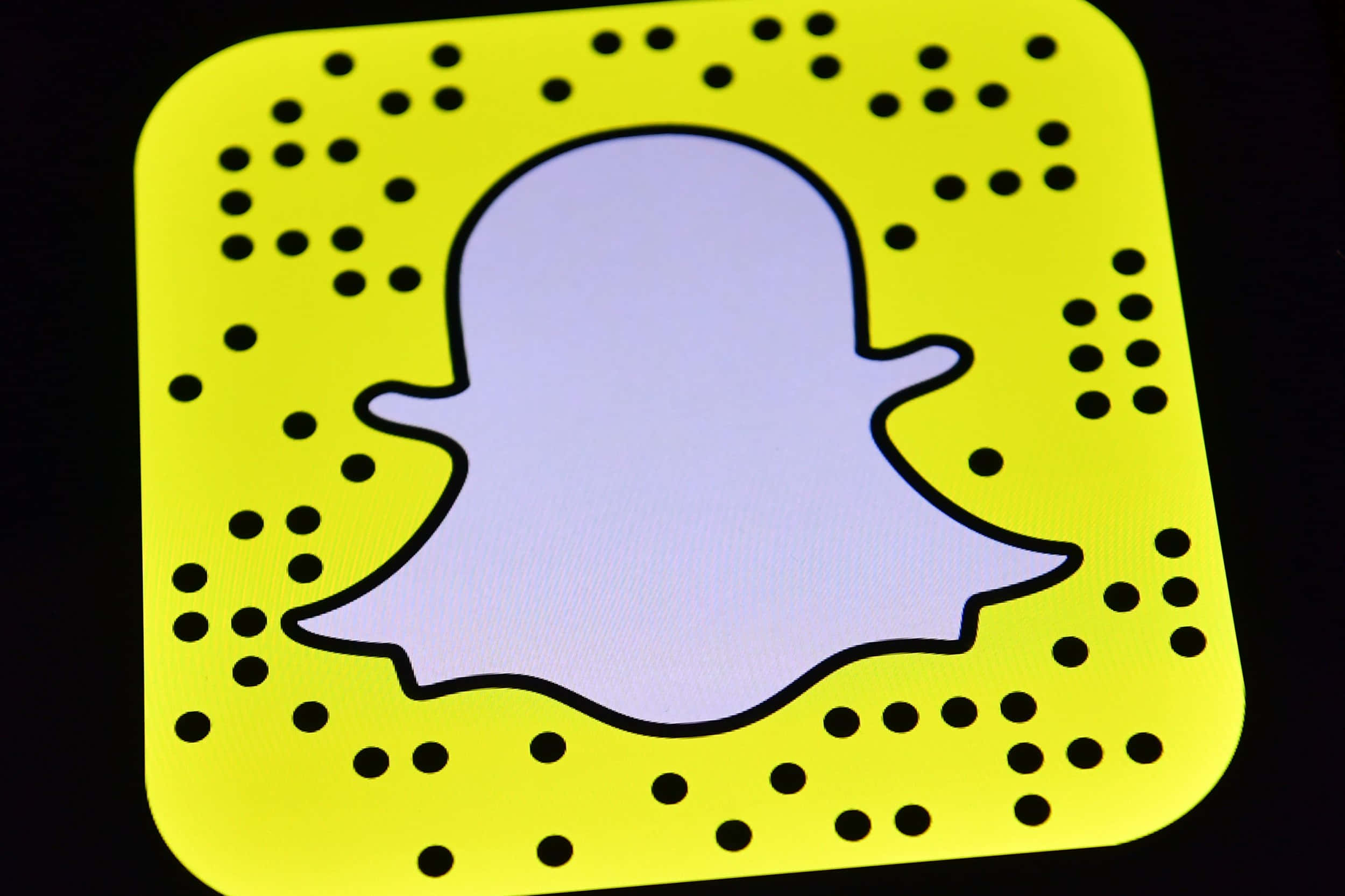 Snapchat 桌布 壁紙 — Snapchat QR 碼特寫，帶有發光黃色背景和圍繞白色鬼魂圖示的黑色點點。