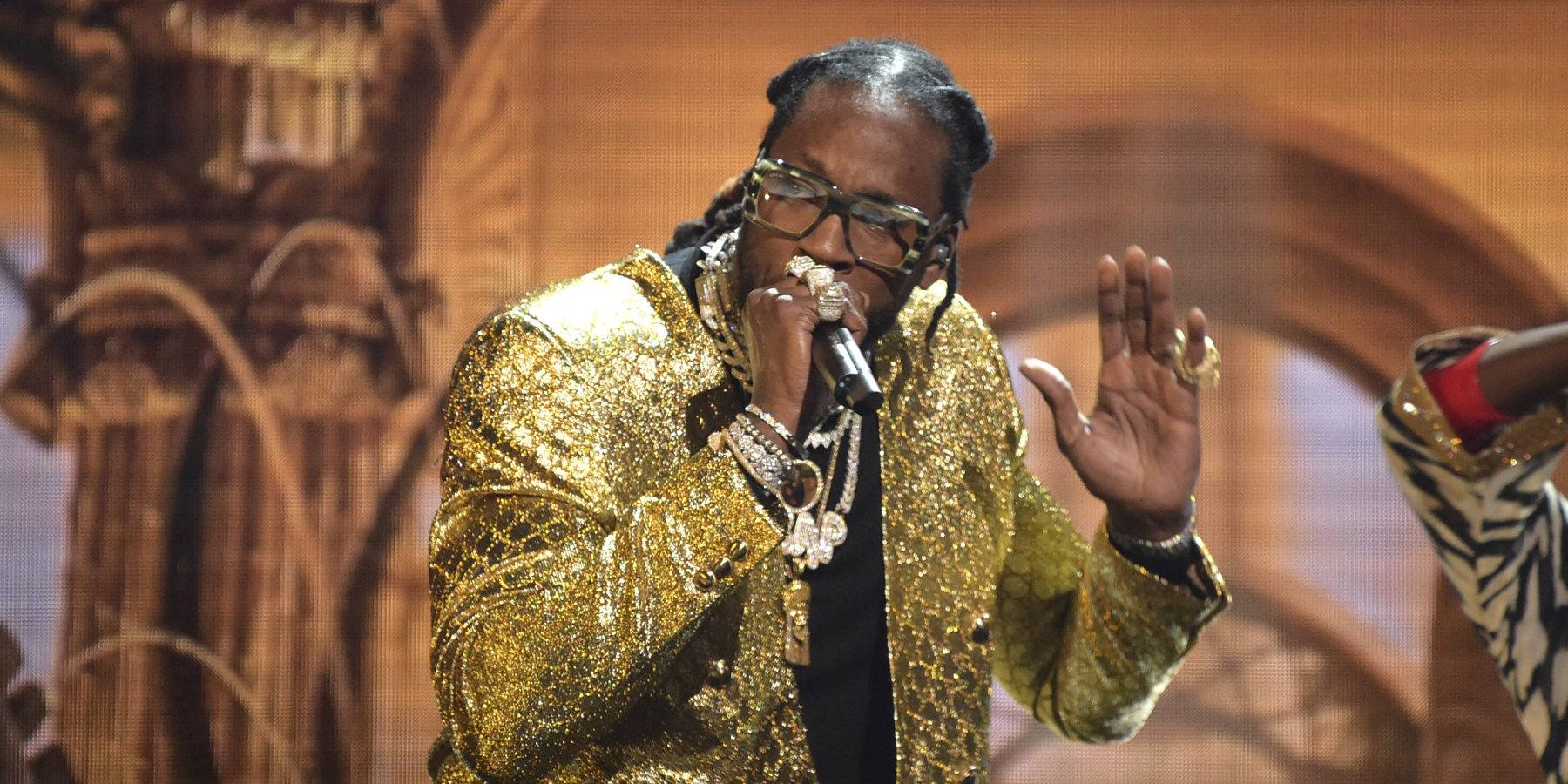 2 Chainz 桌布 壁紙 — Snoop Dogg 在舞台上穿著閃耀的金色亮片外套和眼鏡，手持麥克風表演。