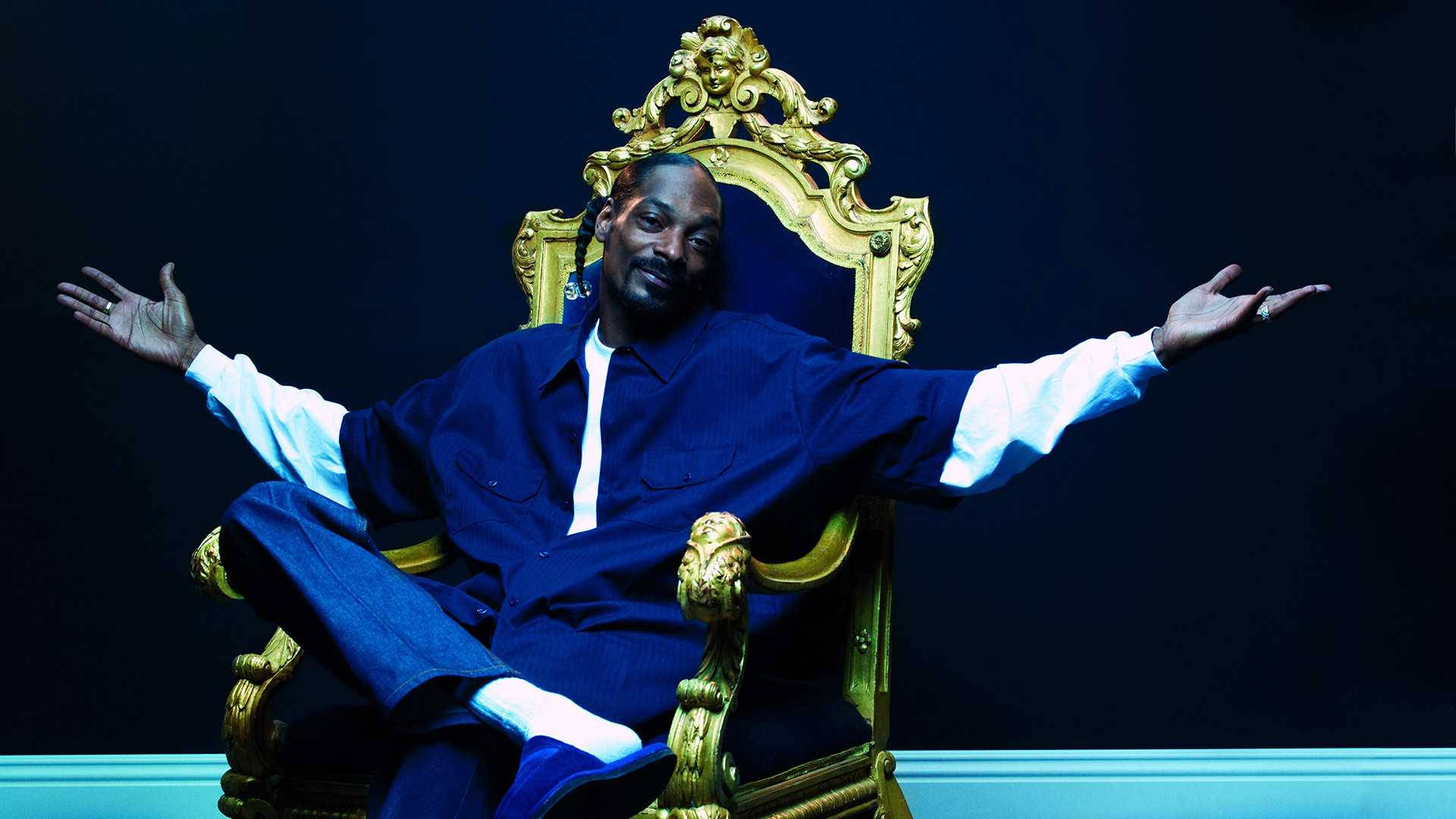 Snoop 桌布 壁紙 — Snoop Dogg 在黑暗背景下，雙臂大開，威嚴地坐在金色王座椅上。