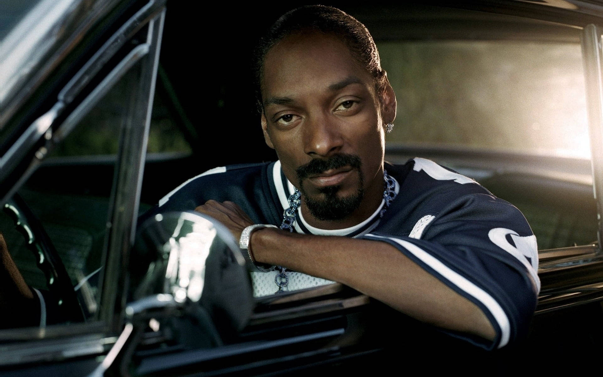 Snoop 桌布 壁紙 — Snoop Dogg 從一輛沐浴在金色背光中的復古車窗中酷酷地探出頭來。