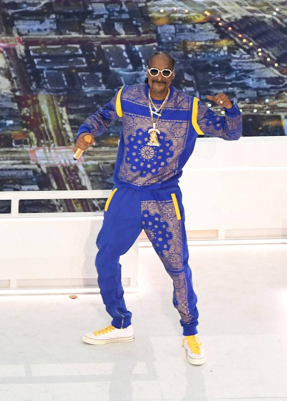 bandana 桌布 壁紙 — Snoop Dogg 身穿大膽的藍黃圖案運動服，在屋頂舞台上自信擺姿勢，身後是城市燈光。