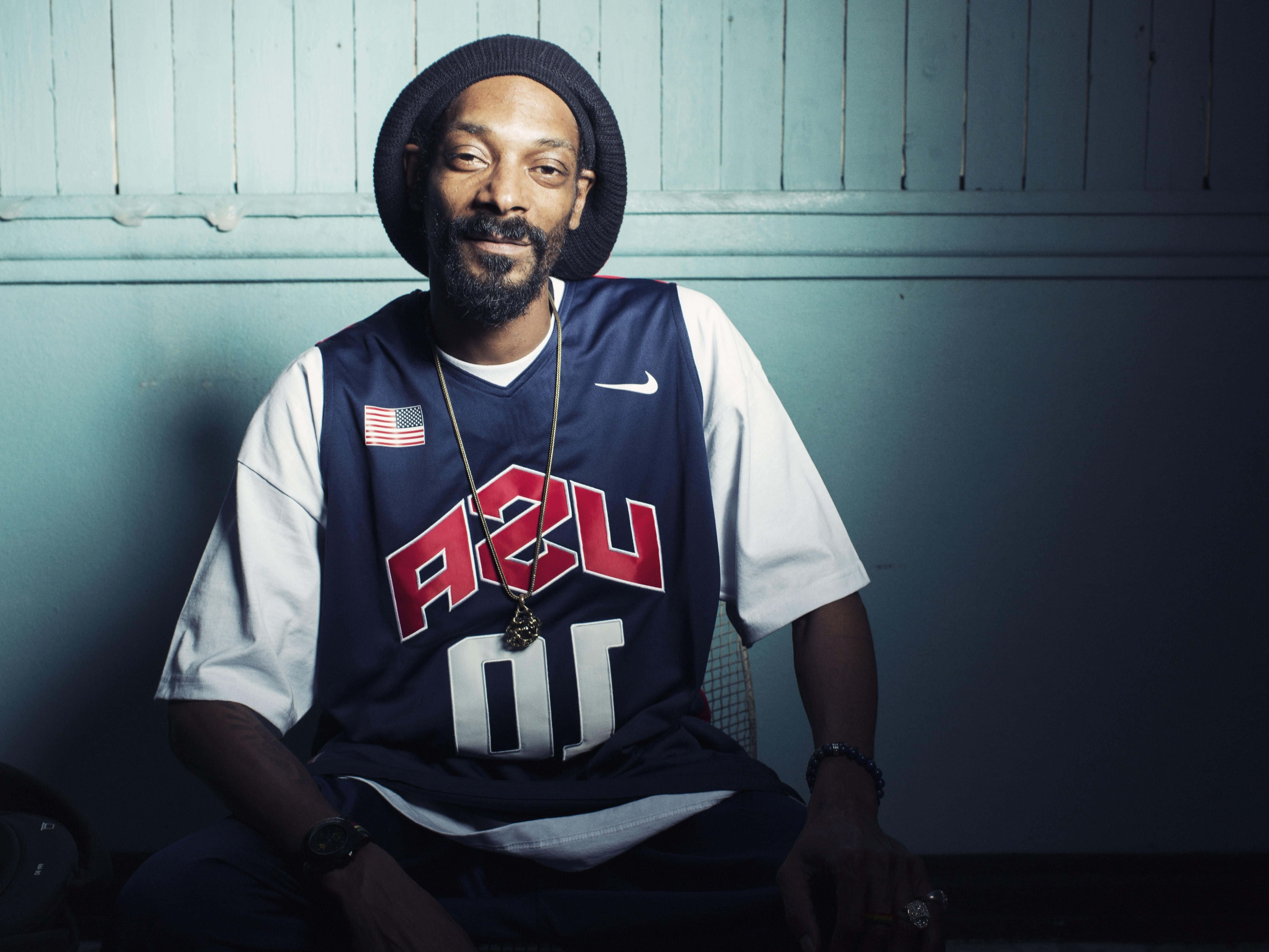 Young Snoop Dogg 桌布 壁紙 — Snoop Dogg 隨意地靠著青綠色鑲板牆，穿著美國籃球球衣和毛帽，在戲劇性的燈光下。