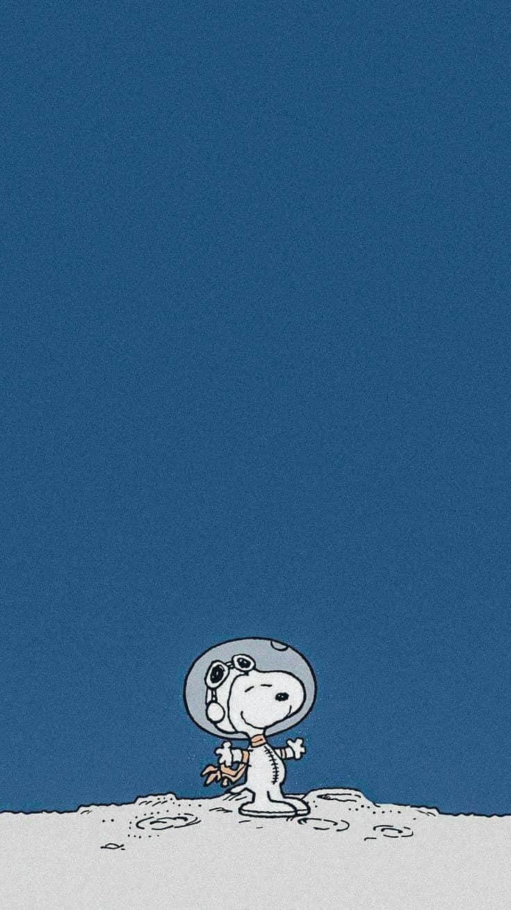  壁紙 — 史努比穿著太空衣，站在月球般的表面上，在廣闊的藍天下，旁邊有一面小旗。