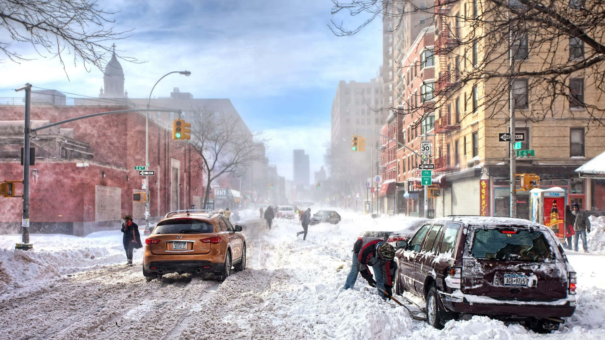 Winter Cityscape 桌布 壁紙 — 白雪覆蓋著繁忙的城市街道，行人和汽車在多雲的天空下穿梭於冬季的城市景觀中。