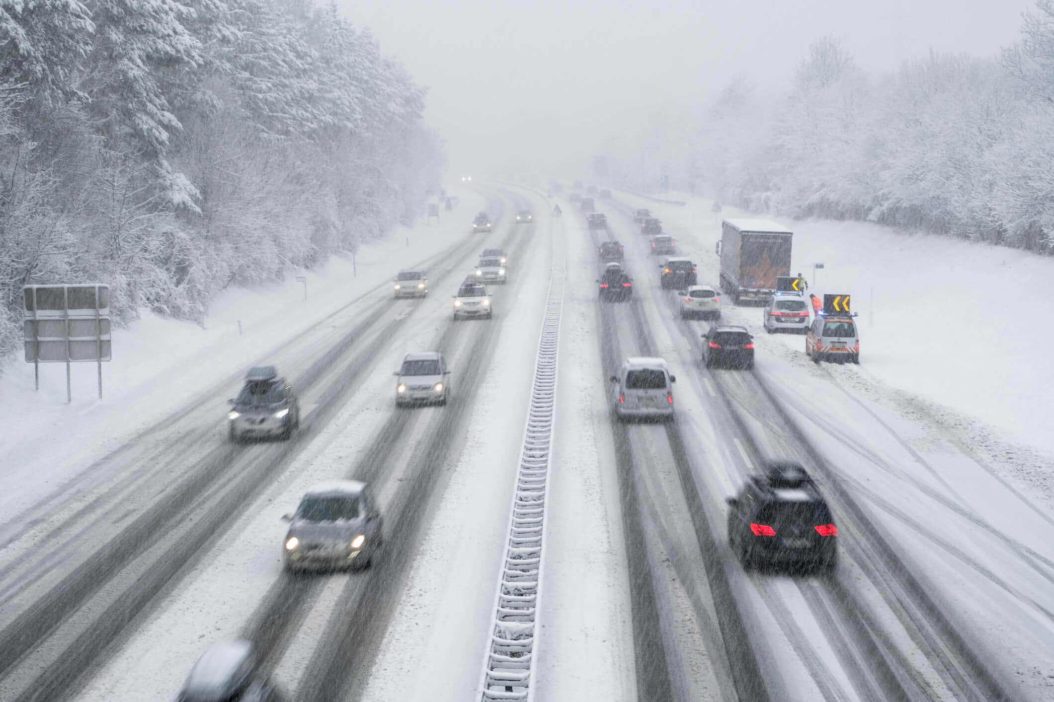 Winter Driving 桌布 壁紙 — 白雪覆蓋多線道的高速公路，汽車在濃霧中行駛，車頭燈刺破白茫茫一片。