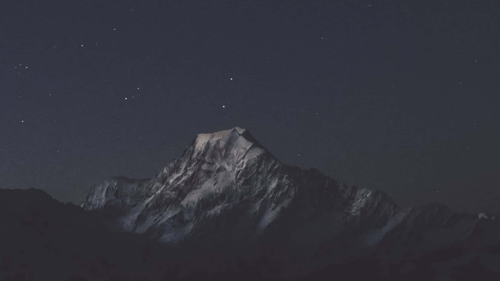  壁紙 — 白雪覆蓋的山峰在繁星點點的夜空下升起，帶有微弱的天體光芒。