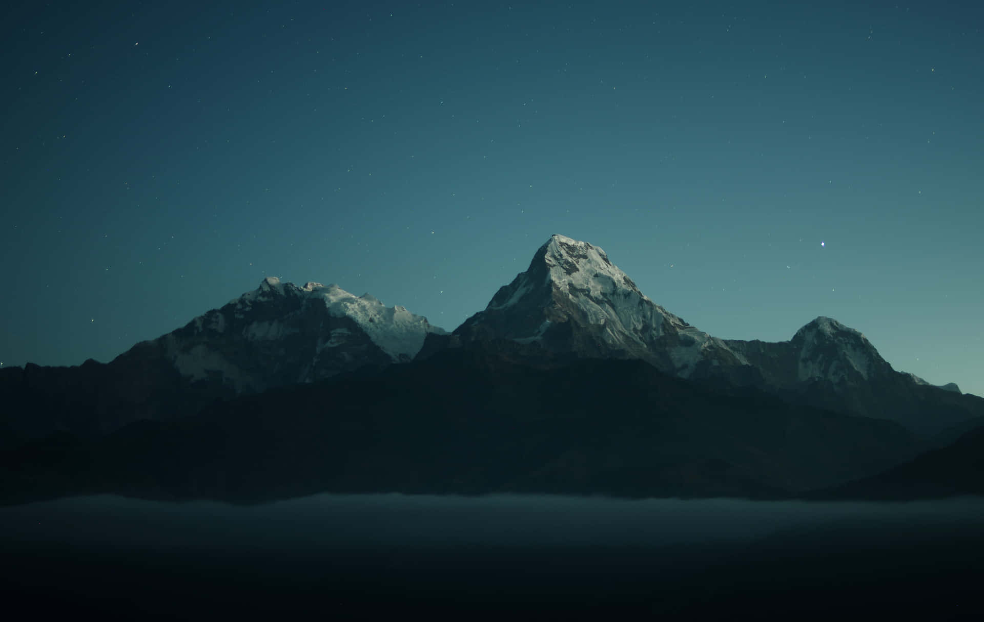 積雪的山峰在星空下的霧氣之上聳立。 — 電腦 壁紙