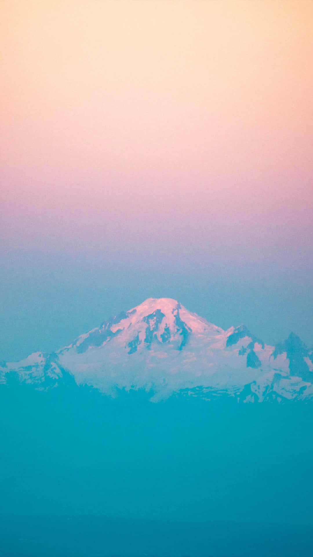  壁紙 — 一座積雪的山峰在暮色中聳立，背景是粉紅、紫色和藍綠色的漸變天空。