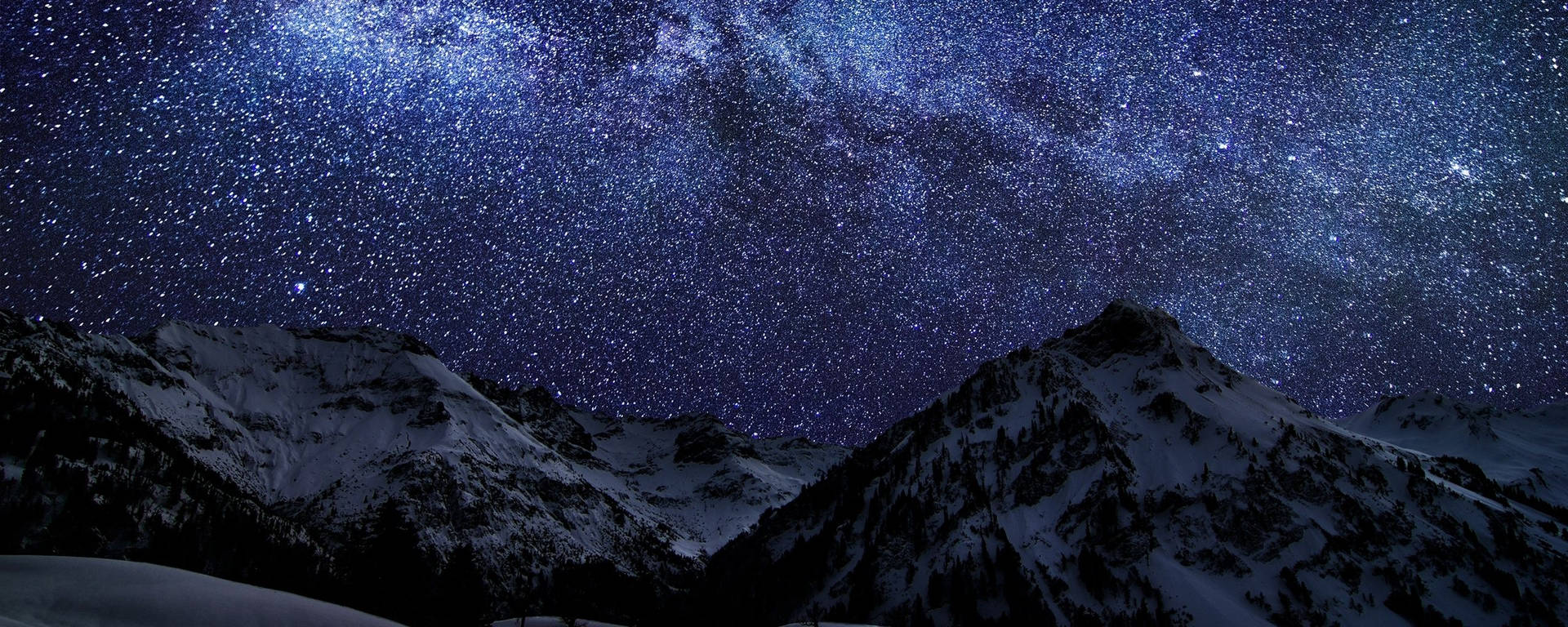 白雪覆蓋的山脈在明亮的星空下，銀河清晰可見。 — 雙螢幕 壁紙