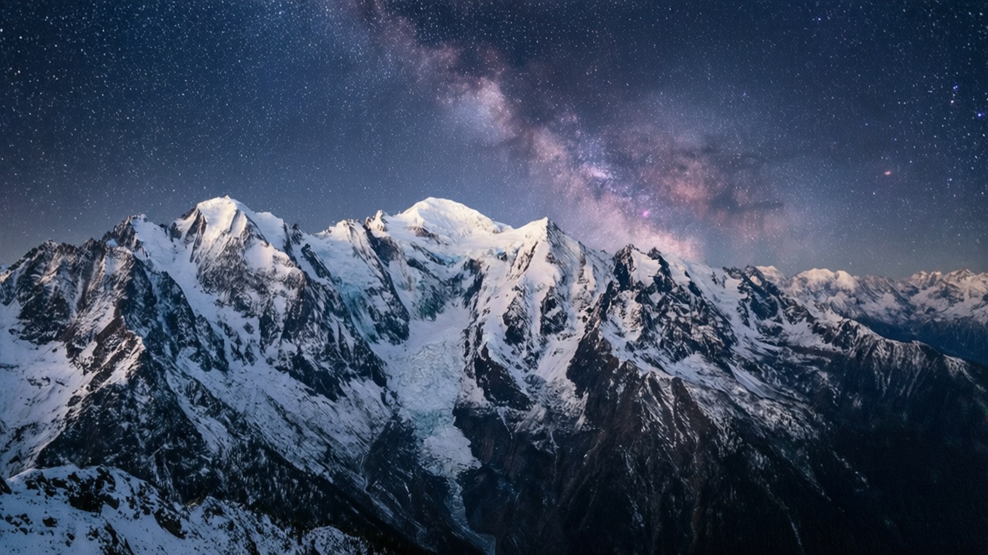 Starry Mountain Range 壁紙 — 積雪的山峰在繁星點點的夜空下聳立，銀河散發著粉紅色和紫色的光芒。