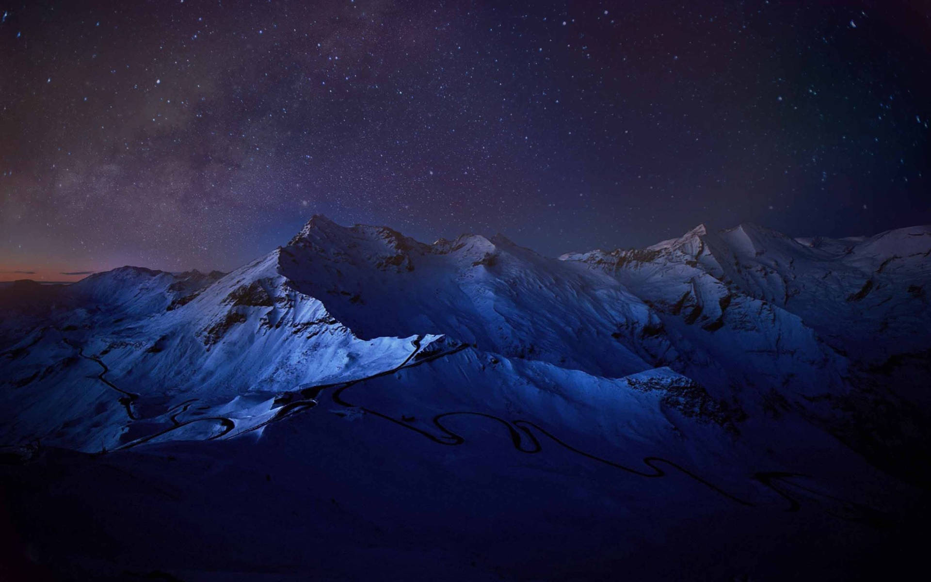 白雪覆蓋的山脈在繁星點點的夜空下，蜿蜒的道路 — Macbook Pro 壁紙