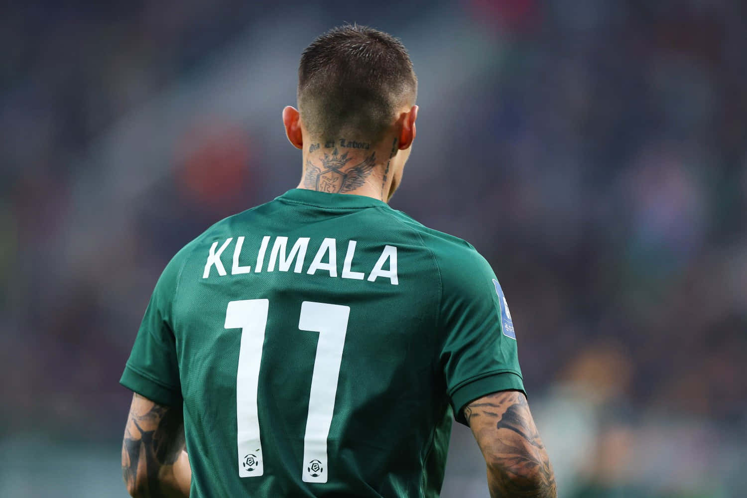  壁紙 — 一名身穿綠色球衣、印有名字KLIMALA和號碼11的足球員背對鏡頭站立，展示頸部和手臂上的刺青。