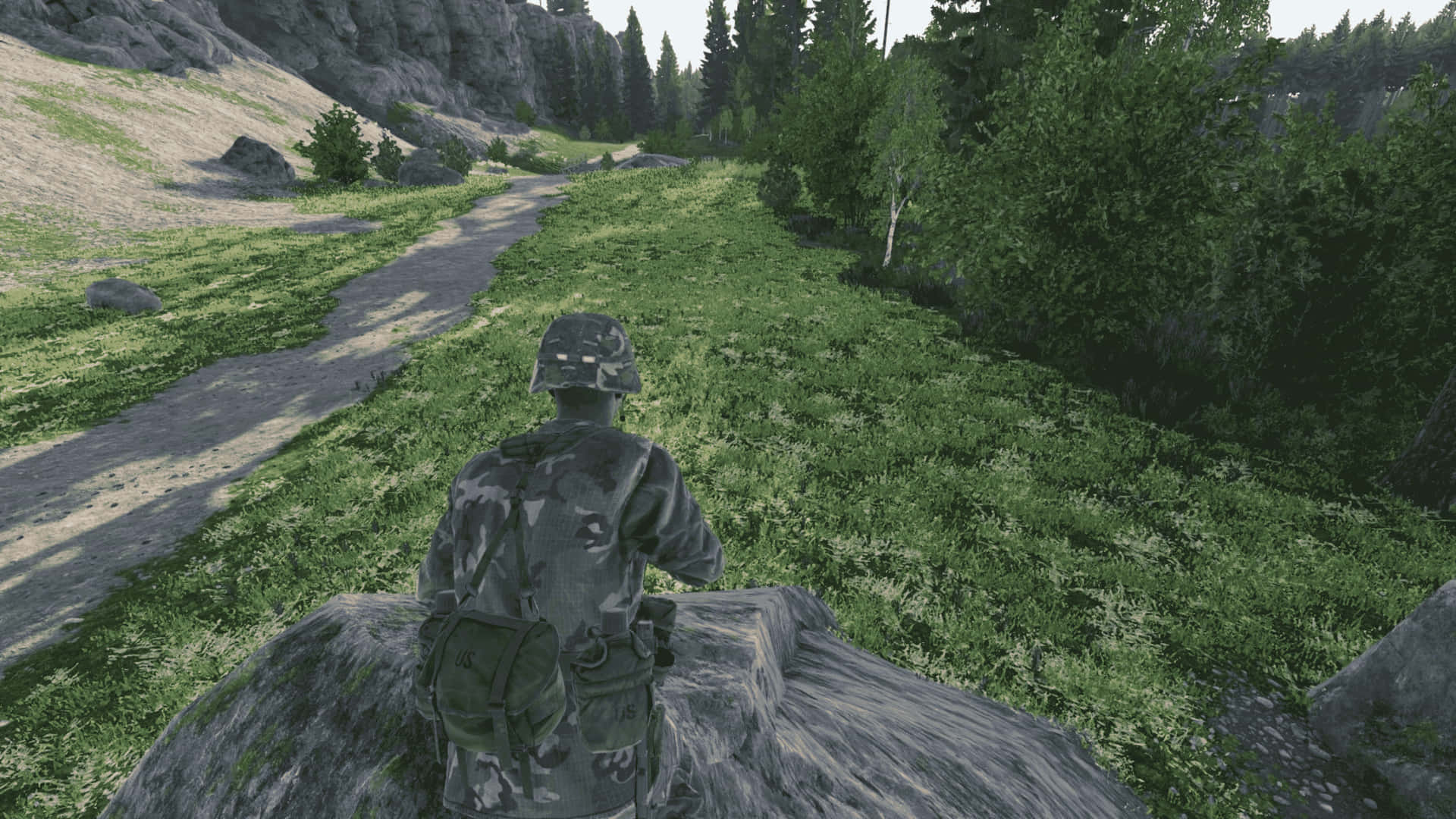 身穿迷彩裝備的士兵從岩石山丘上俯瞰森林小徑。 — 4K 壁紙