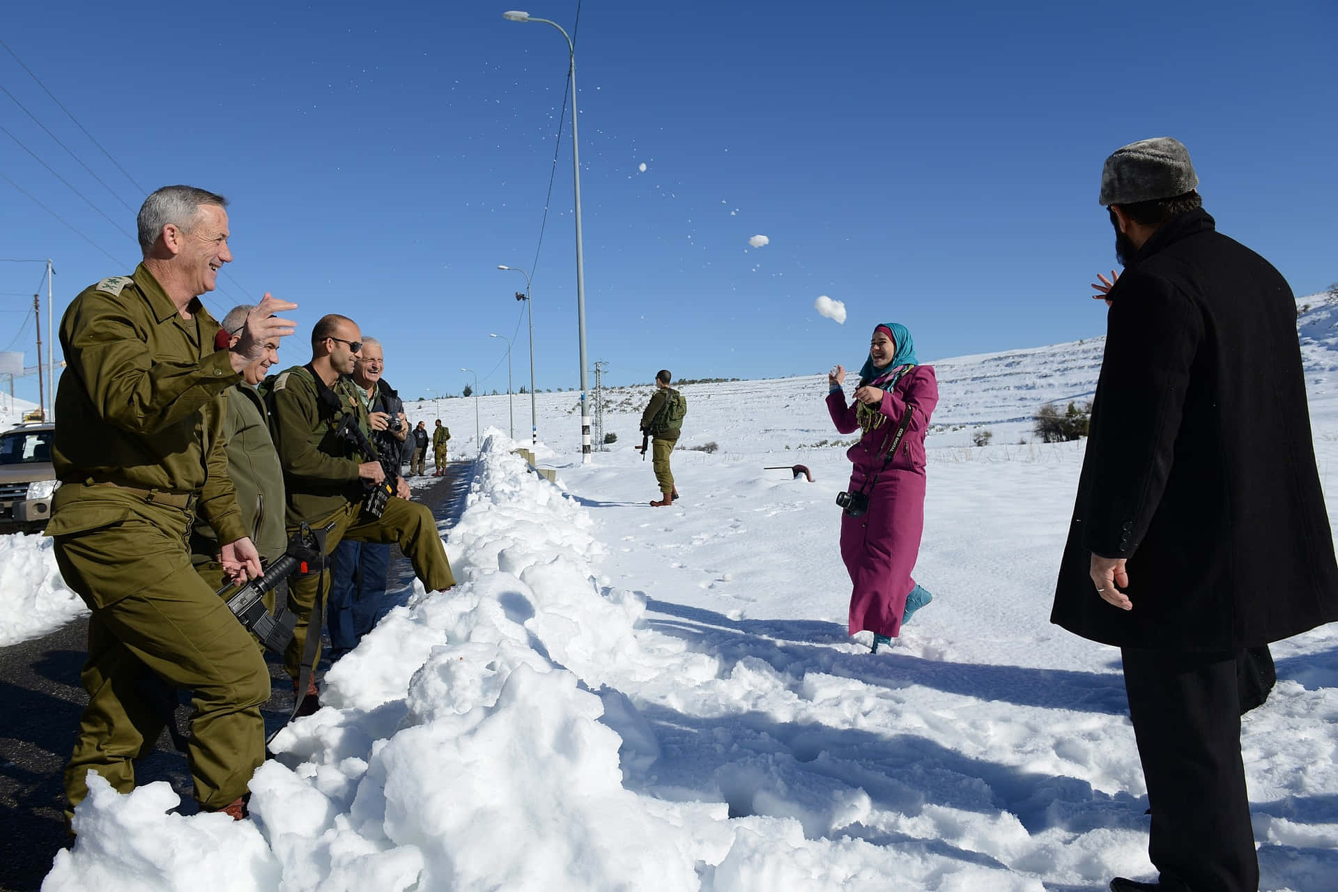  壁紙 — 士兵和市民在明亮陽光的冬日風景中開心地丟雪球。