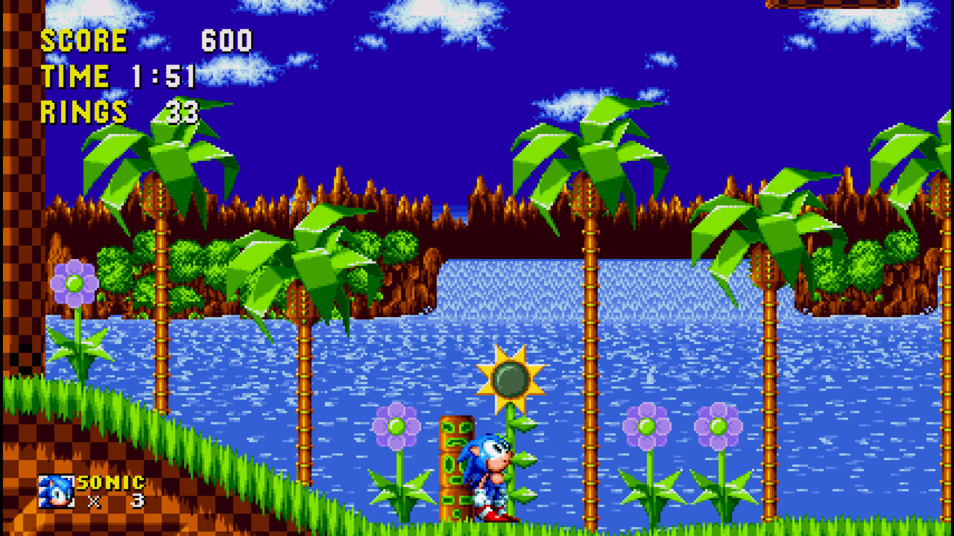 電玩遊戲 桌布 壁紙 — Sonic the Hedgehog 在陽光明媚的天空下，穿過一個充滿活力的像素叢林關卡，有棕櫚樹和藍色河流。