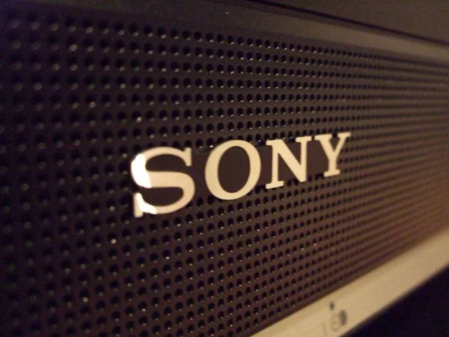 Sony 桌布 壁紙 — Sony 喇叭格柵的特寫，金屬標誌在溫暖的環境光下發光。