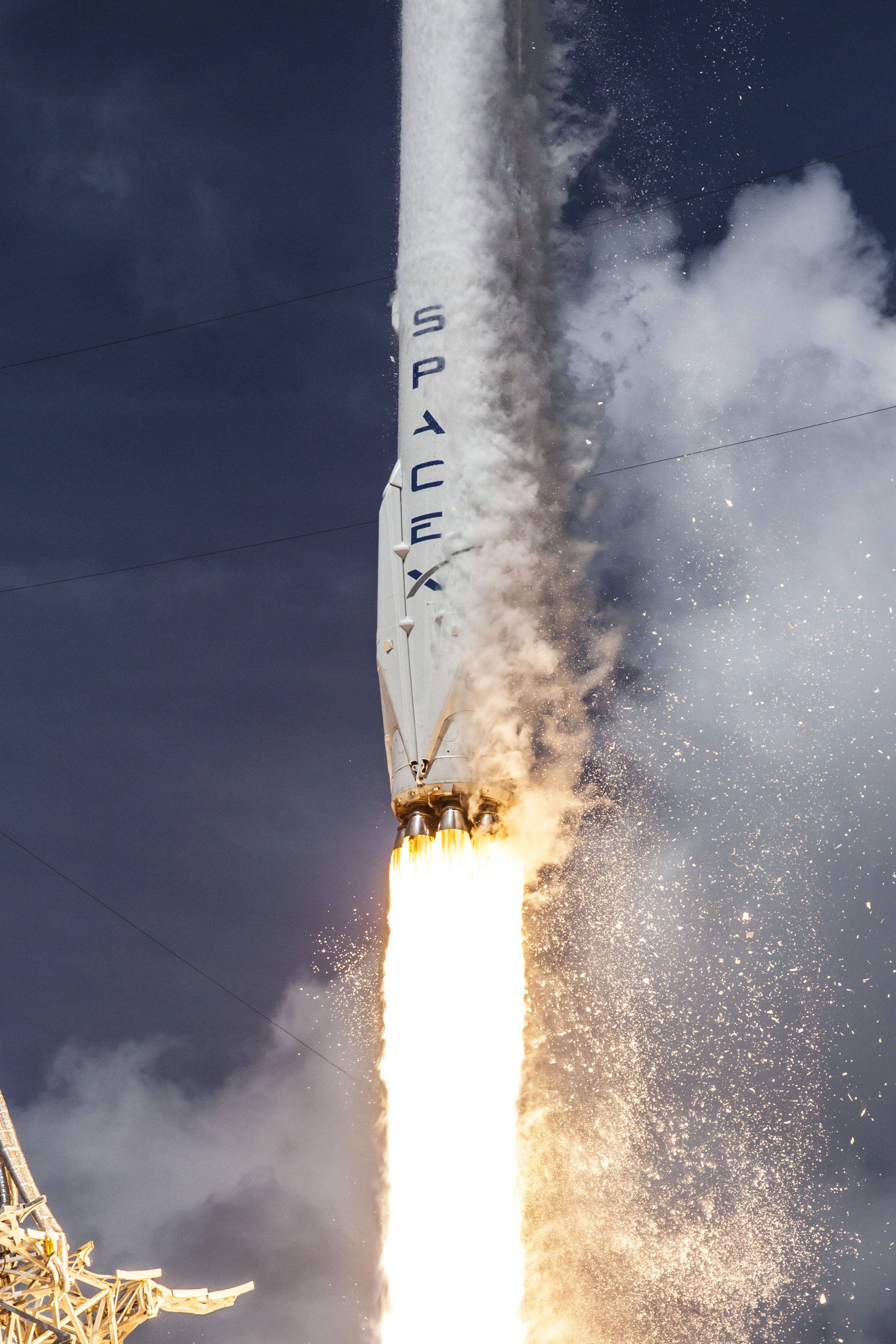 SpaceX 桌布 壁紙 — SpaceX 火箭在陰暗多雲的天空中向上發射，伴隨著熾熱的推力和滾滾濃煙。