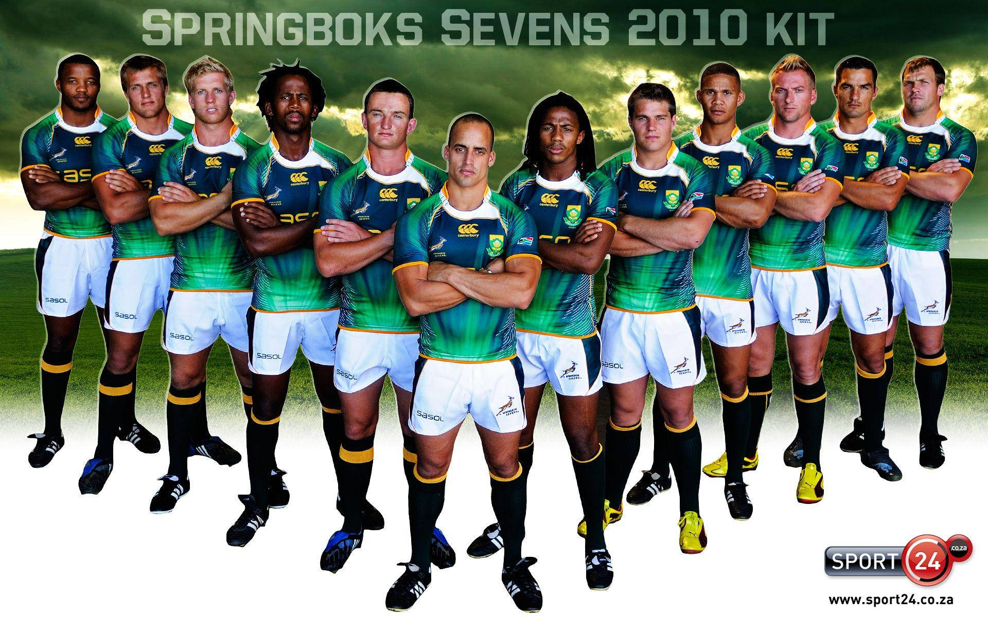 橄欖球 桌布 壁紙 — Springboks Sevens 欖球隊穿著2010年綠色和白色球衣，在戲劇性的天空下，在草地上自信地交叉雙臂擺姿勢。