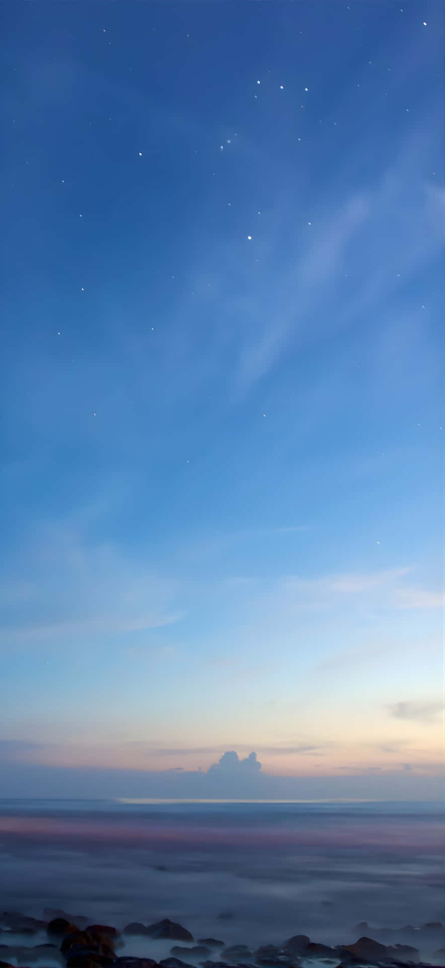  壁紙 — 星光暮色天空，有柔軟雲朵和寧靜海浪拍打暗色岩石。