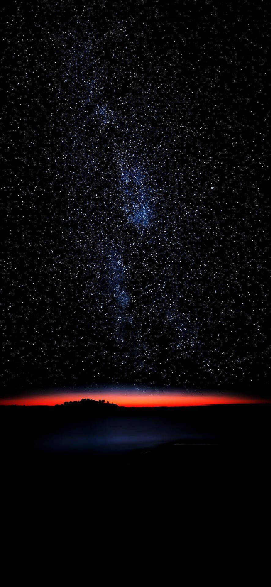 繁星點點的夜空，紅色地平線在黑暗的大地輪廓上方 — Galaxy S10 壁紙